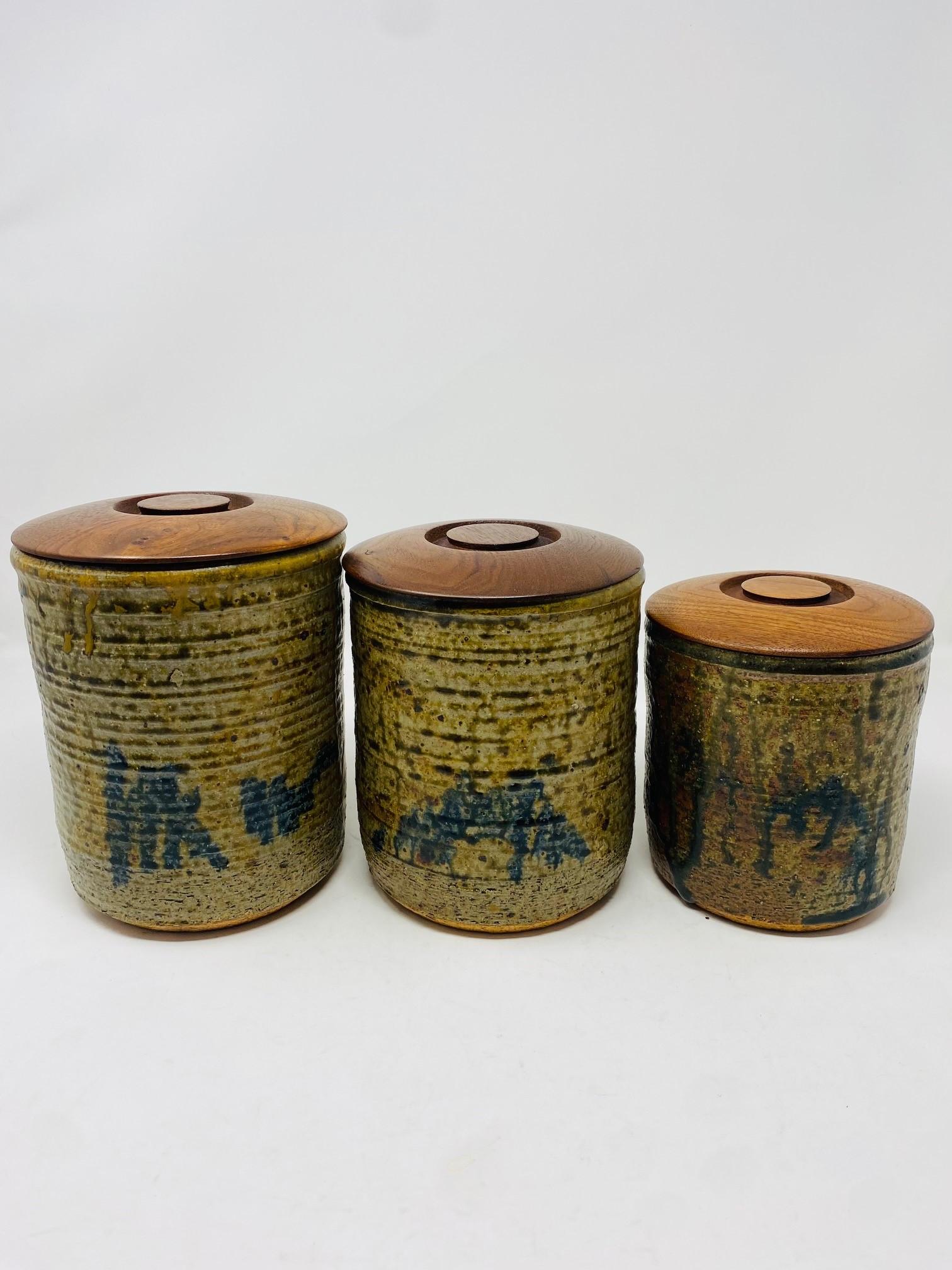 Beautifully crafted set of 3 original ceramic canisters that present craftsmanship and style.  This set includes canisters in 3 different sizes.  Each is presented with its own walnut lid with a circular design that aesthetically creates a timeless