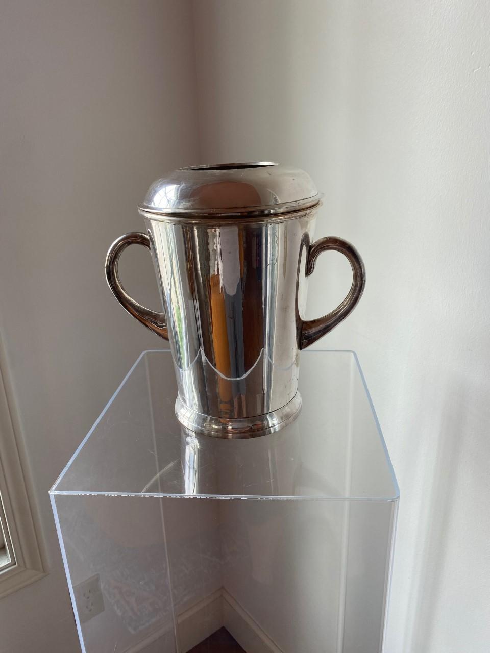 Beautiful clean lined silver plated ice bucket. This piece is late 1950s and stands the test of time. The beautiful vessel design is held by 2 handles at the side, with a clever lid that snaps in place allowing for bottle to handsomely stand