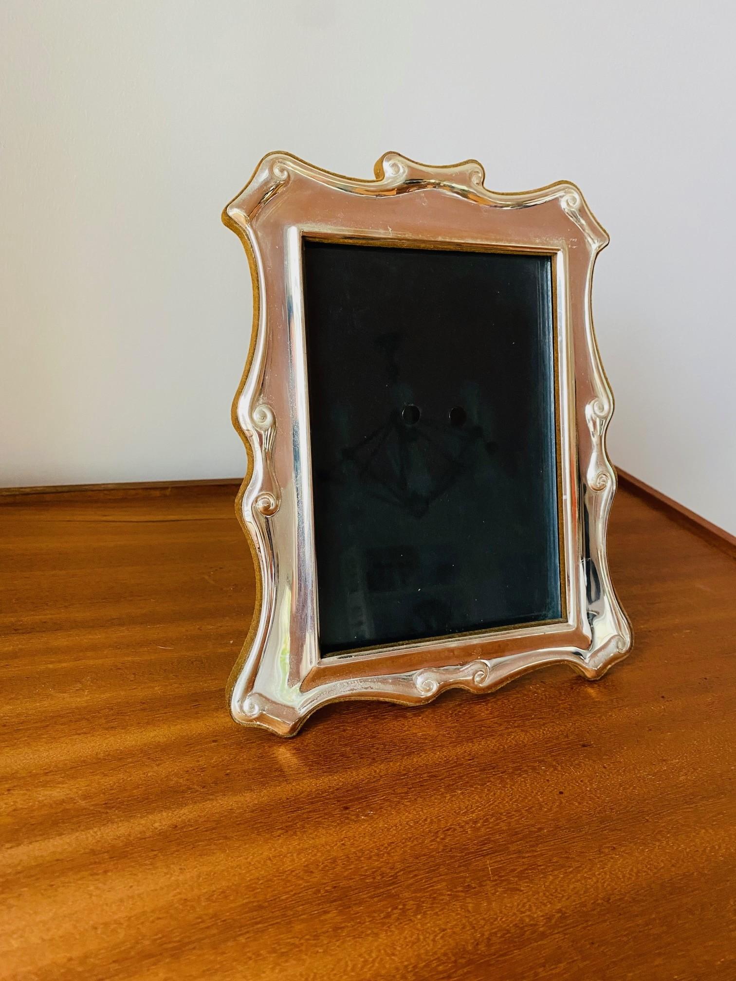 Stylish and architectural silver plated vintage photo frame.  A legacy in design, Carrs of Sheffield proposes whimsical design for home decor.  This beautiful piece exudes silver metal glow as it is completely enveloped in a beautiful green suede