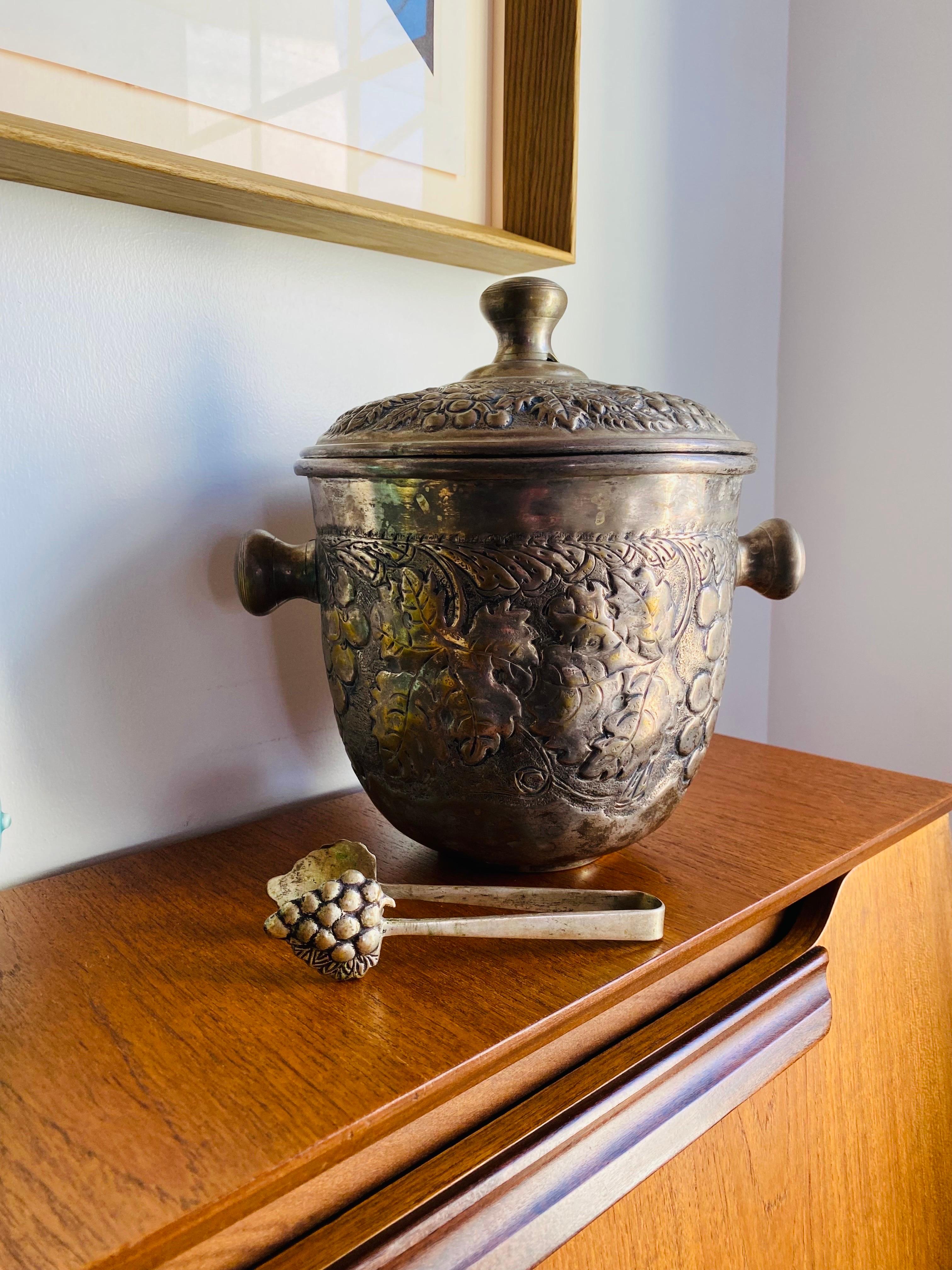 Beautiful vintage repousse finish brass silverplated ice bucket with tongs.  This beautifully aged piece from the 1960s has incredible patina and will add style to any bar or decor style.  Classic and unique.  

Mid-Century, Hollywood Regency, Art