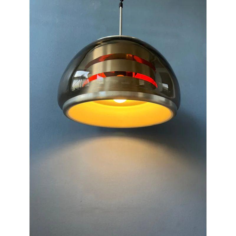 Space age pendant light with a smoked glass shade, presumably Herda or Lakro. The lamp consists of a glass outer shade and aluminium inner shade. The lamp requires four E27/26 lightbulbs.

Dimensions:
ø: 33 cm
Height (shade): 25 cm

Condition:
