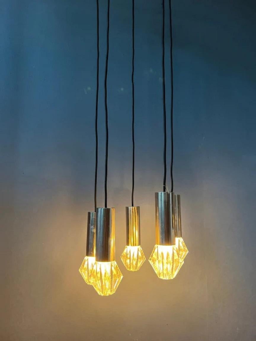 Mid century space age cascade pendant lamp / light fixture with 5 glass shades. The shades can easily be adjusted in height. The lamp requires five E14 lightbulbs.

Dimensions: 
ø Shade: 7 cm
ø Full Lamp: 45 cm
Height (adjustable): 120 - 60