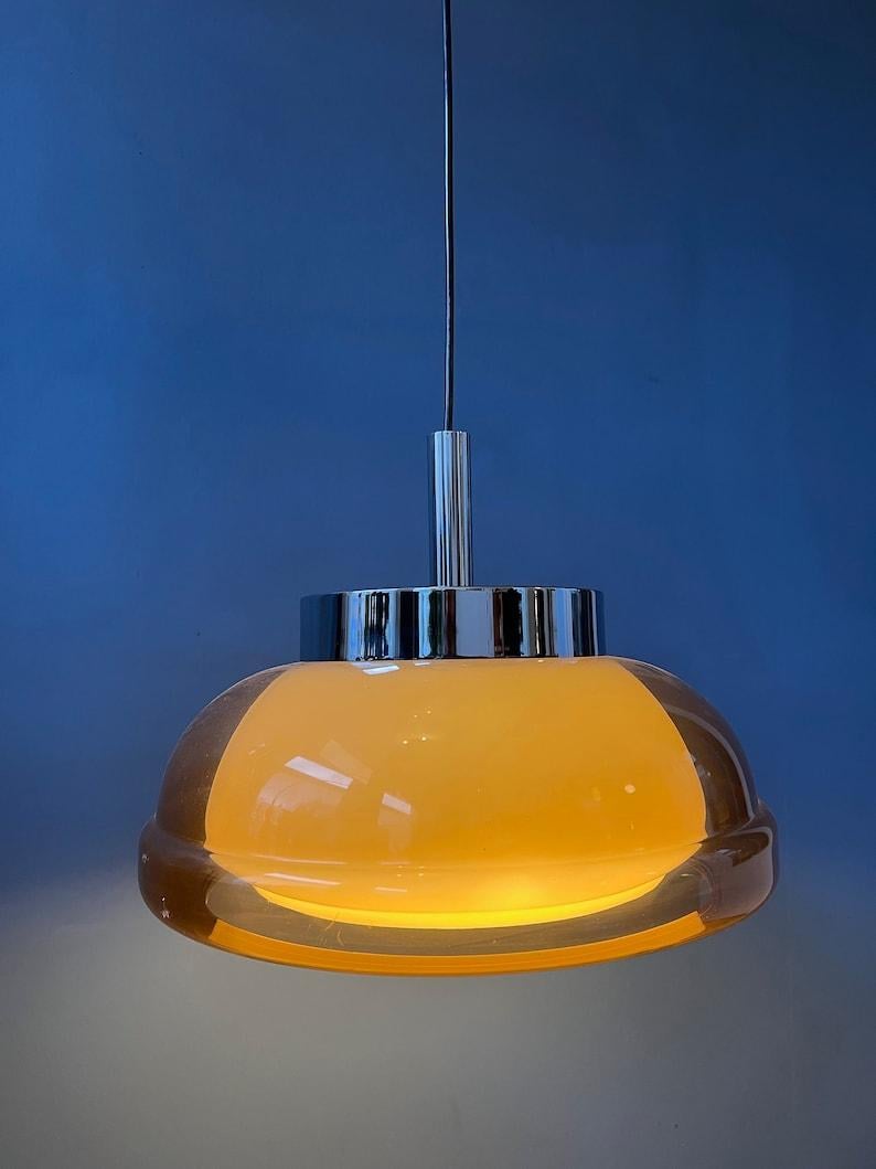 A very special space age pendant by the Dutch brand Herda. The lamp consists of an acryllic orange/brown/copper coloured outer shade and a white inner shade. The lamp requires one E27 lightbulb.

Additional information:
Materials: Metal,
