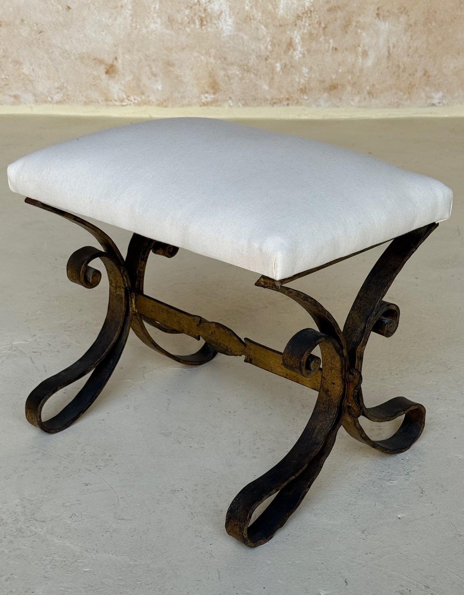 This elegant vintage mid century Spanish gilt iron bench features an ornate base with gracefully scrolled legs and a decorative central stretcher. The rich gilt finish is hand applied. In very good vintage condition, it measures 14 inches high,