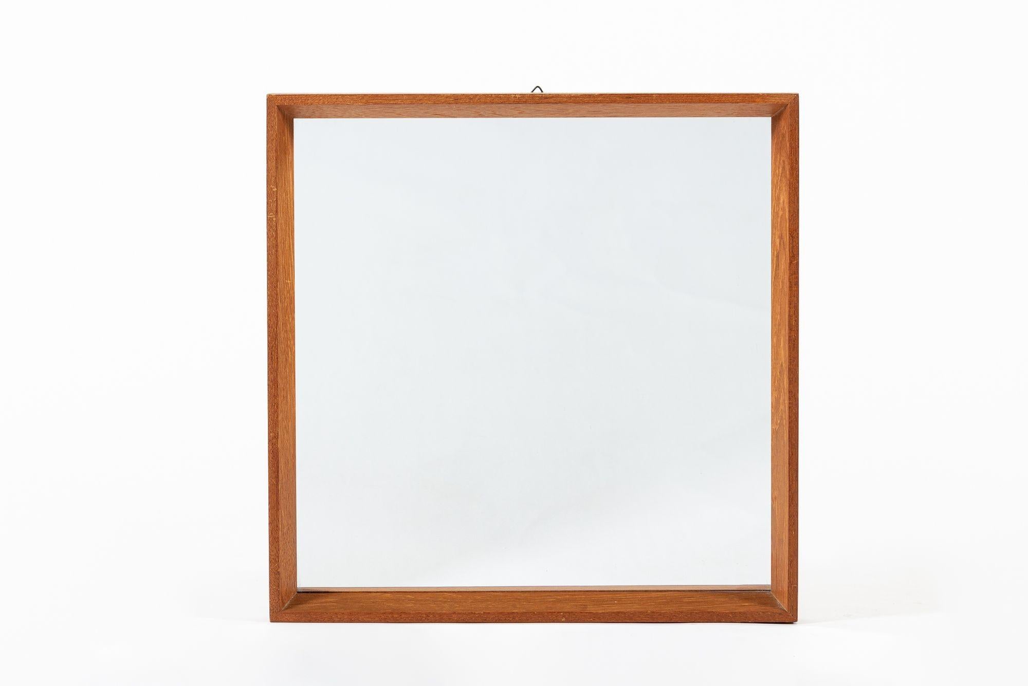 Questo delizioso specchio da parete vintage della metà del secolo scorso risale al 1960 circa. Presenta un design pulito e minimalista con una cornice quadrata in legno con un semplice smusso angolare, realizzata in teak massiccio. Include la