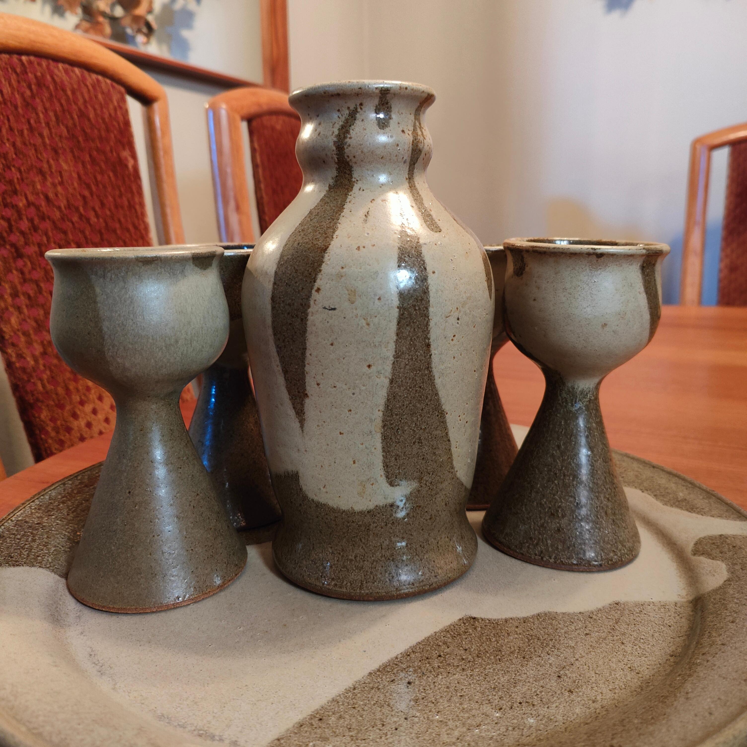 Just in is a beautiful studio made ceramic wine set. This set includes 1 charger plate, 1 pourer, and 8 goblets. Measurements: Charger plate: 16 inches wide x 1 inch tall; wine pourer: 9.25t x 5 inches wide (at widest point); goblets: approximately