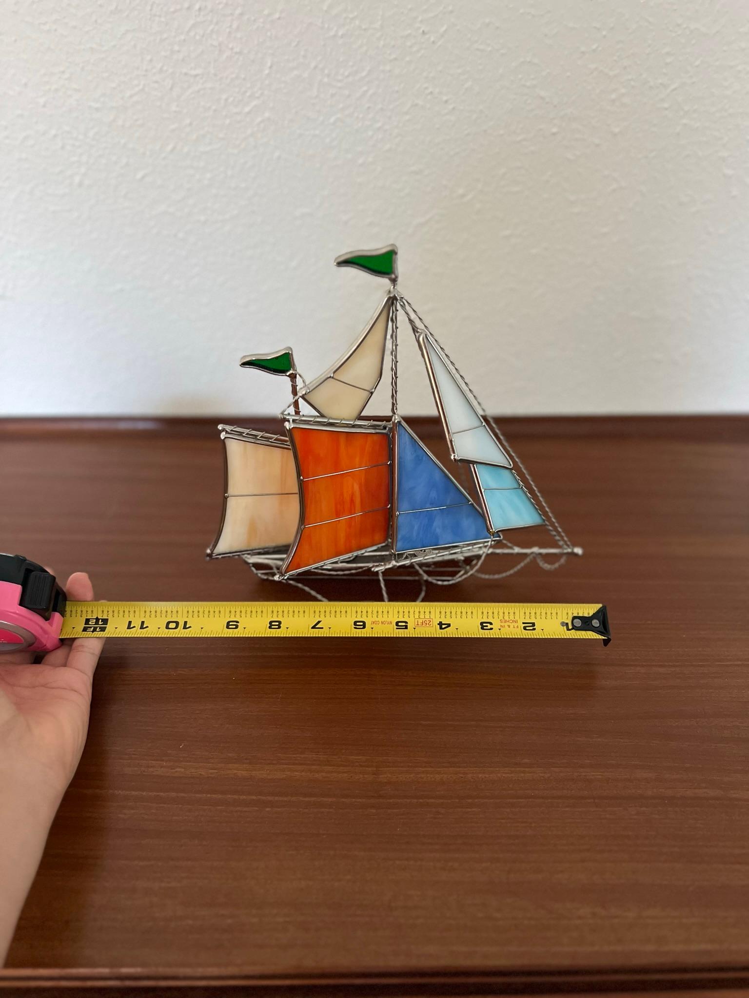 Beautiful handcrafted stained glass sailboat ship. This is a really nice sailboat constructed from stained glass and other metals. It displays well on a shelf or desk. Great for the nautical lover. In excellent condition.

Ship measures