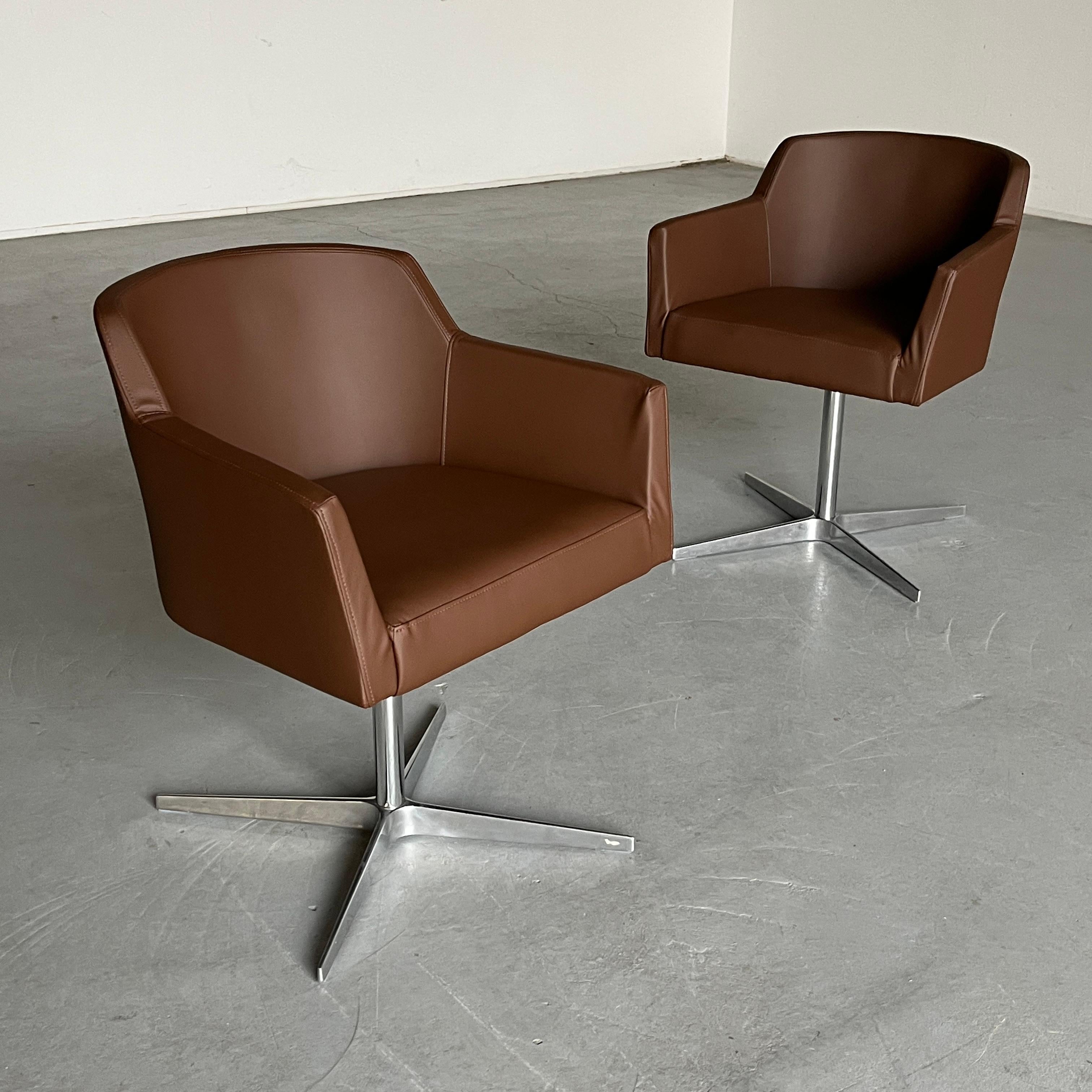One of two vintage mid-century modern armchairs reupholstered in brown faux leather with a chromed steel swivel base.

In good vintage condition with smaller expected signs of age, as shown in the photos. Reupholstered. The base features ‘drop’ like