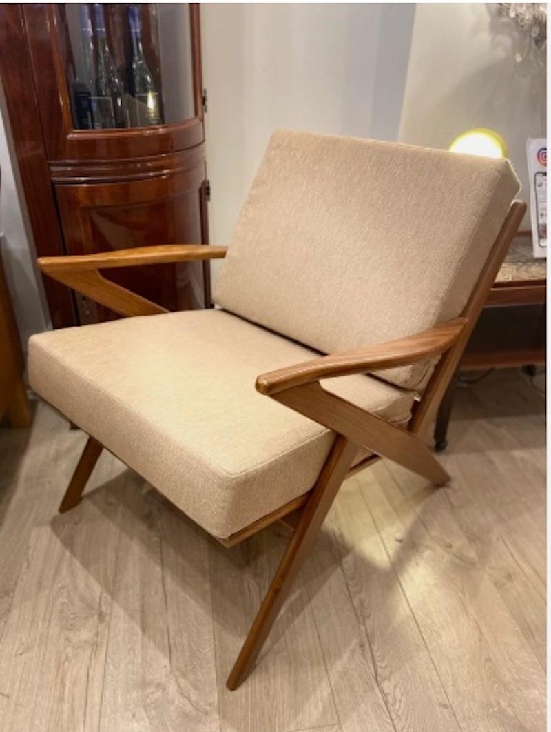 Raffinato esempio di design moderno di metà secolo, questa sedia d'accento in teak presenta linee scultoree e angolate sui braccioli, una struttura in teak massiccio dai toni caldi che mettono in risalto le venature naturali del teak. 

Rivestito in