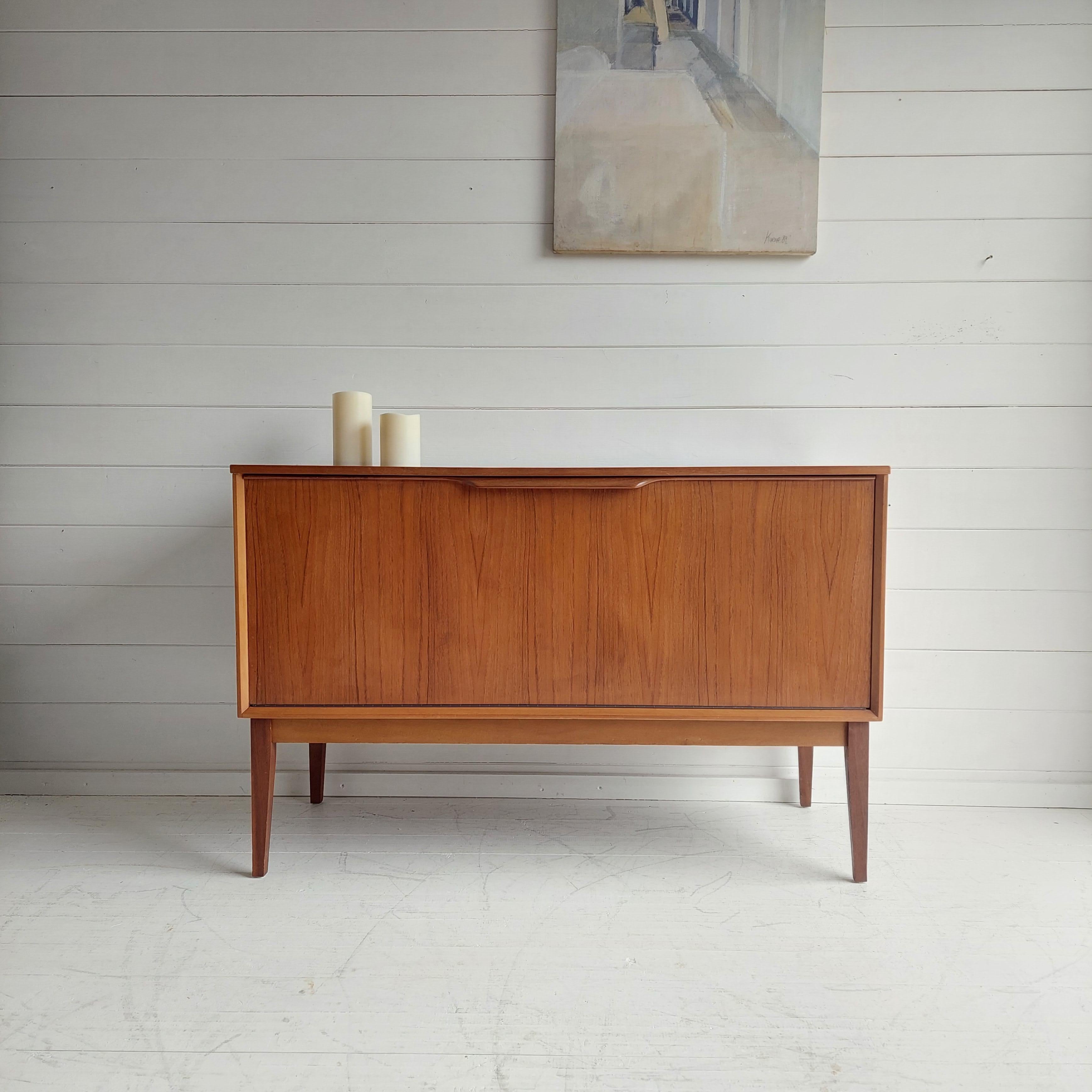A beautifully designed & crafted, Mid Century vinyl record cabinet manufactured by Dynatron.

Featuring minimal clean lines with drop down front to reveal a large storage area with six vertical vinyl dividers. 
Perfect for displaying a turntable and