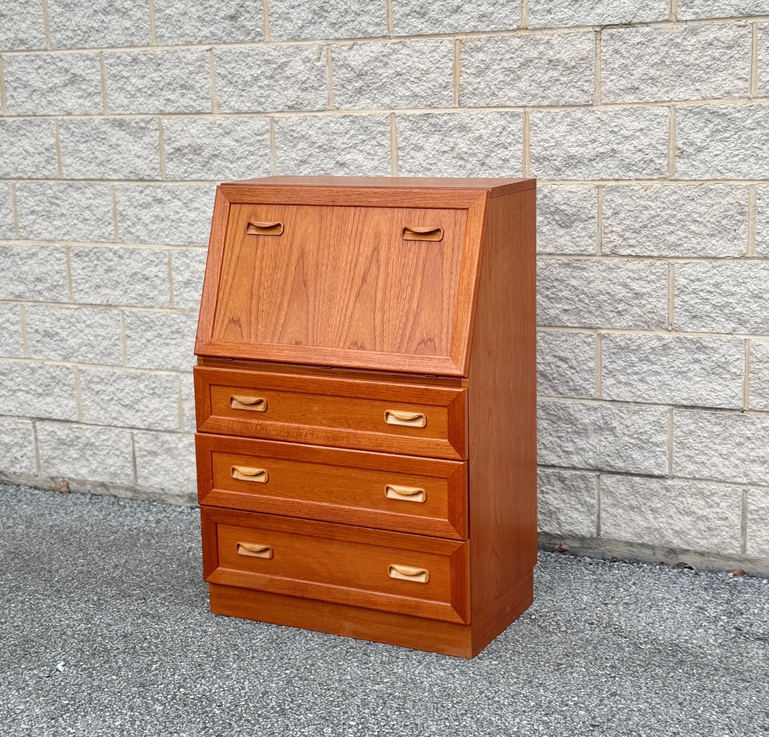 Un superbe bureau vintage en teck de G-Plan, fabriqué en Angleterre vers 1975. Il est doté d'un élégant rabat angulaire qui s'ouvre pour révéler une surface d'écriture en cuir doré, ainsi que des compartiments aménagés, des casiers et des étagères