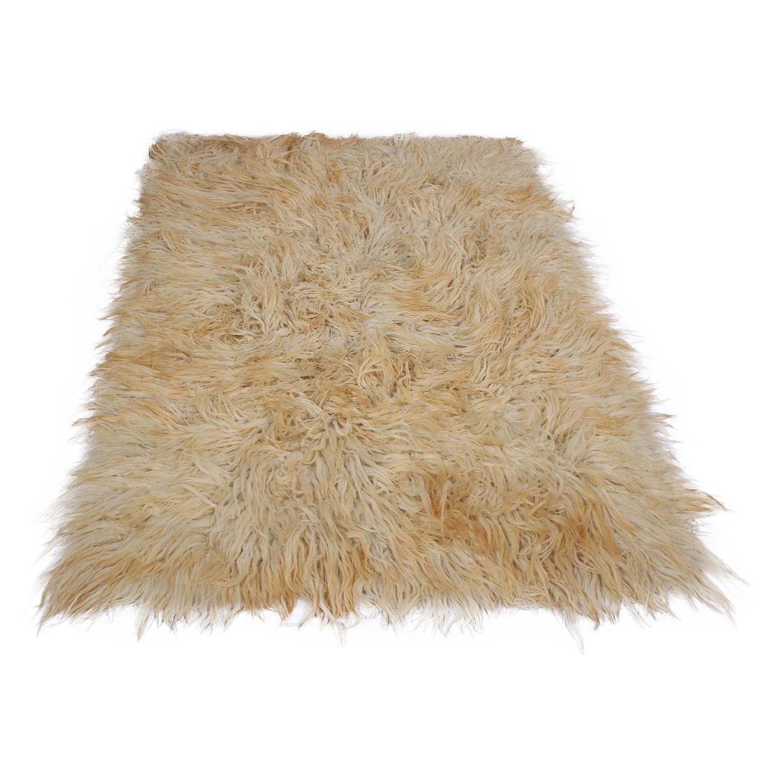 Hand knotted in Turkey originating between 1950-1960, this vintage midcentury Tulu rug offers a distinguished shag pile height with an inviting, plush texture, complemented by the warm, radiant cream and beige-brown colorway as well as the versatile