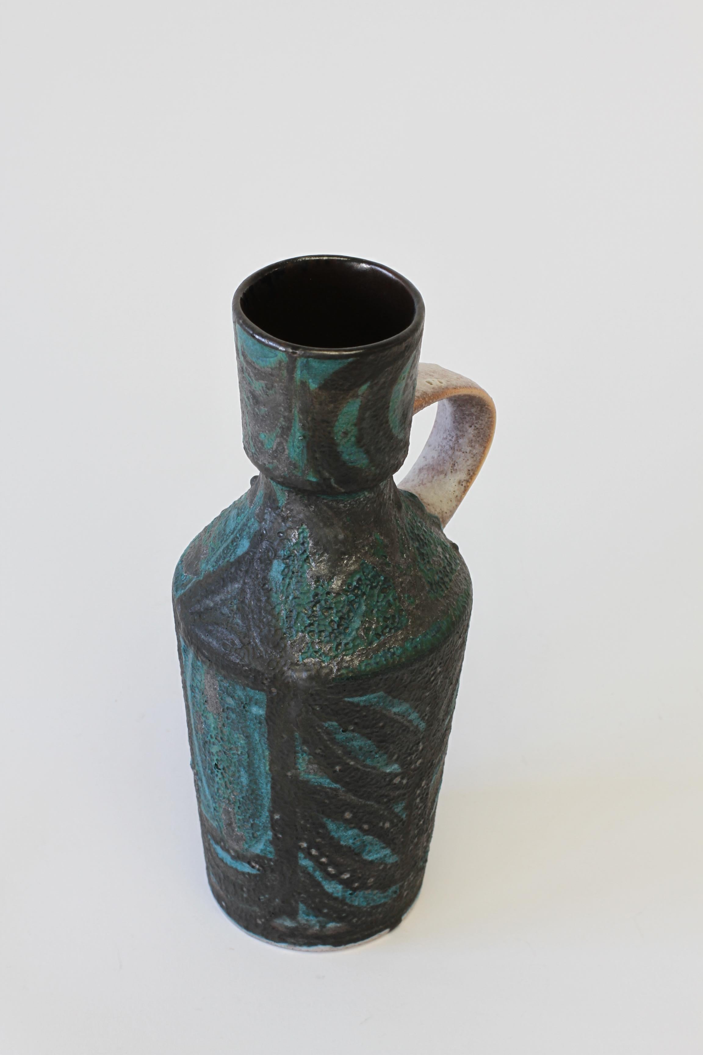 Midcentury vintage vase produced by an unknown maker. This vessel was probably produced in West Germany or Italy somewhere in the 1960s or 1970s. Beautiful form decorated with a deep teal green color with sweeping black accents, grey handle and