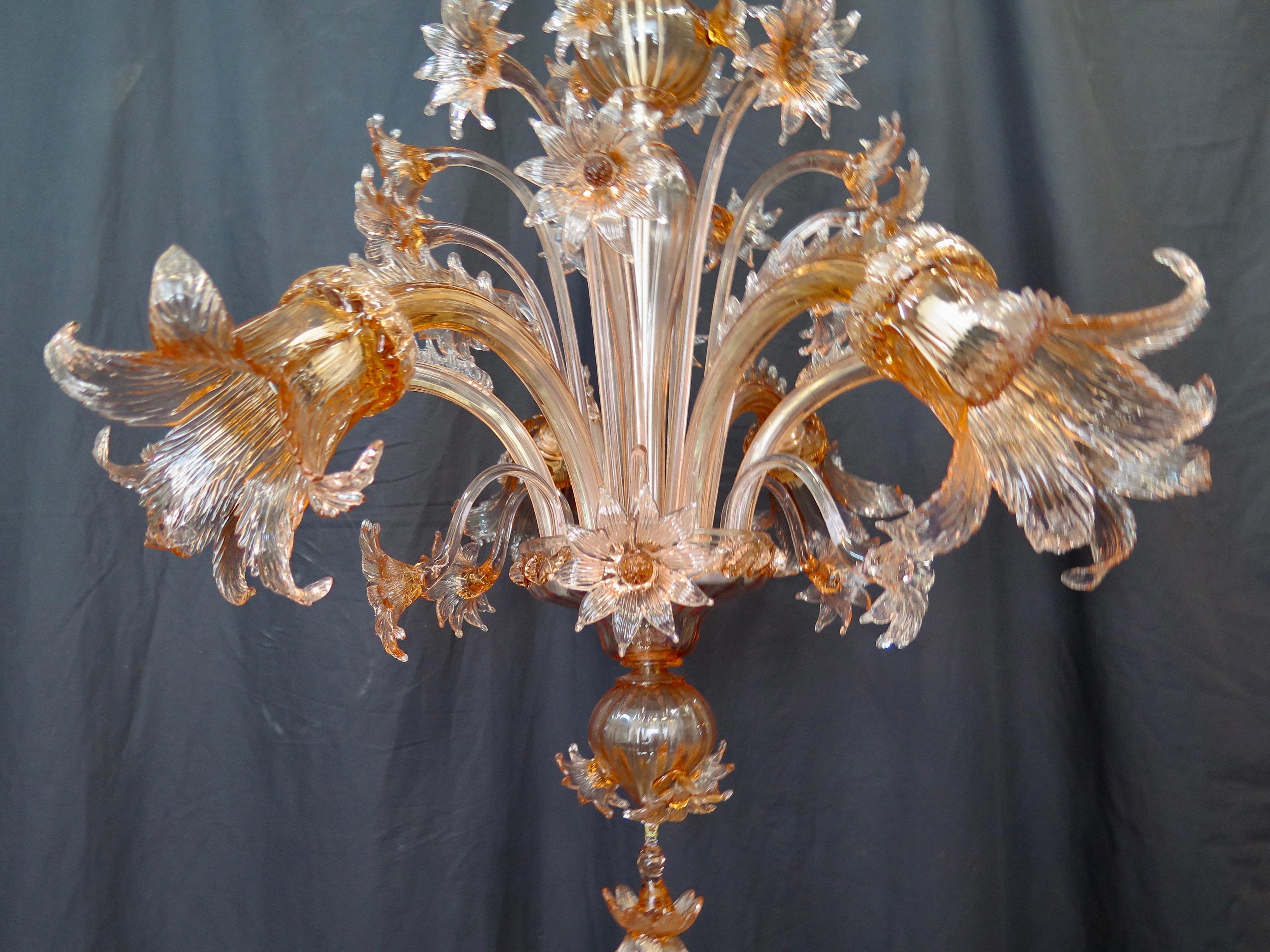 This exquisite mid-20th century Venetian glass chandelier is stylishly decorated with wonderful hand blown champagne pink Murano glass. Six curved glass arms holding stunning stylized glass floral shades extend out from the body of the fixture.