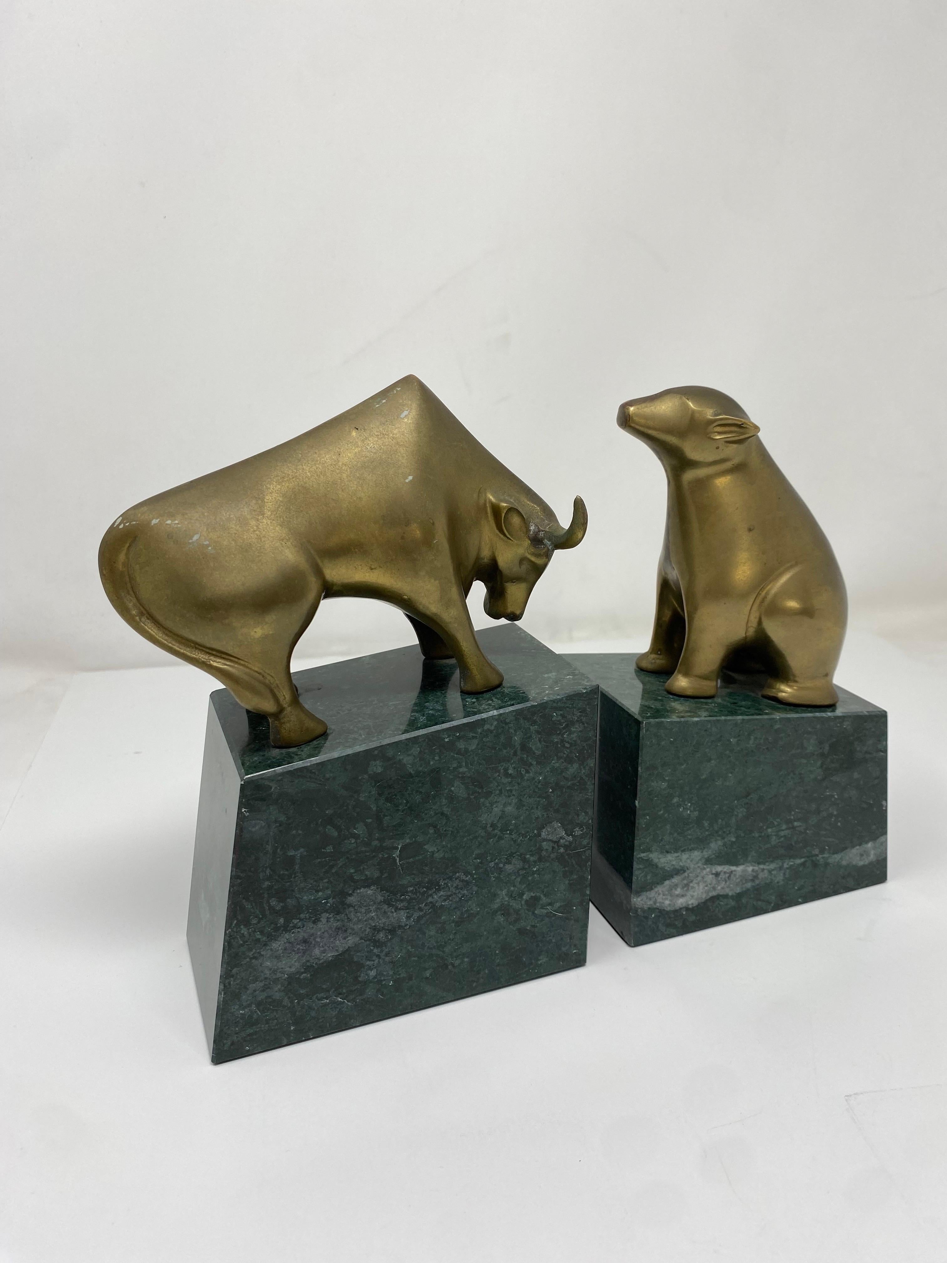 Fermalibri in ottone con toro e orso su base di marmo. Questi simboli iconici di Wall Street sono presentati maestosamente su basi di marmo che aggiungono una solida (letteralmente) essenza di stile. Unico e pieno di stile. Un'ottima aggiunta al tuo