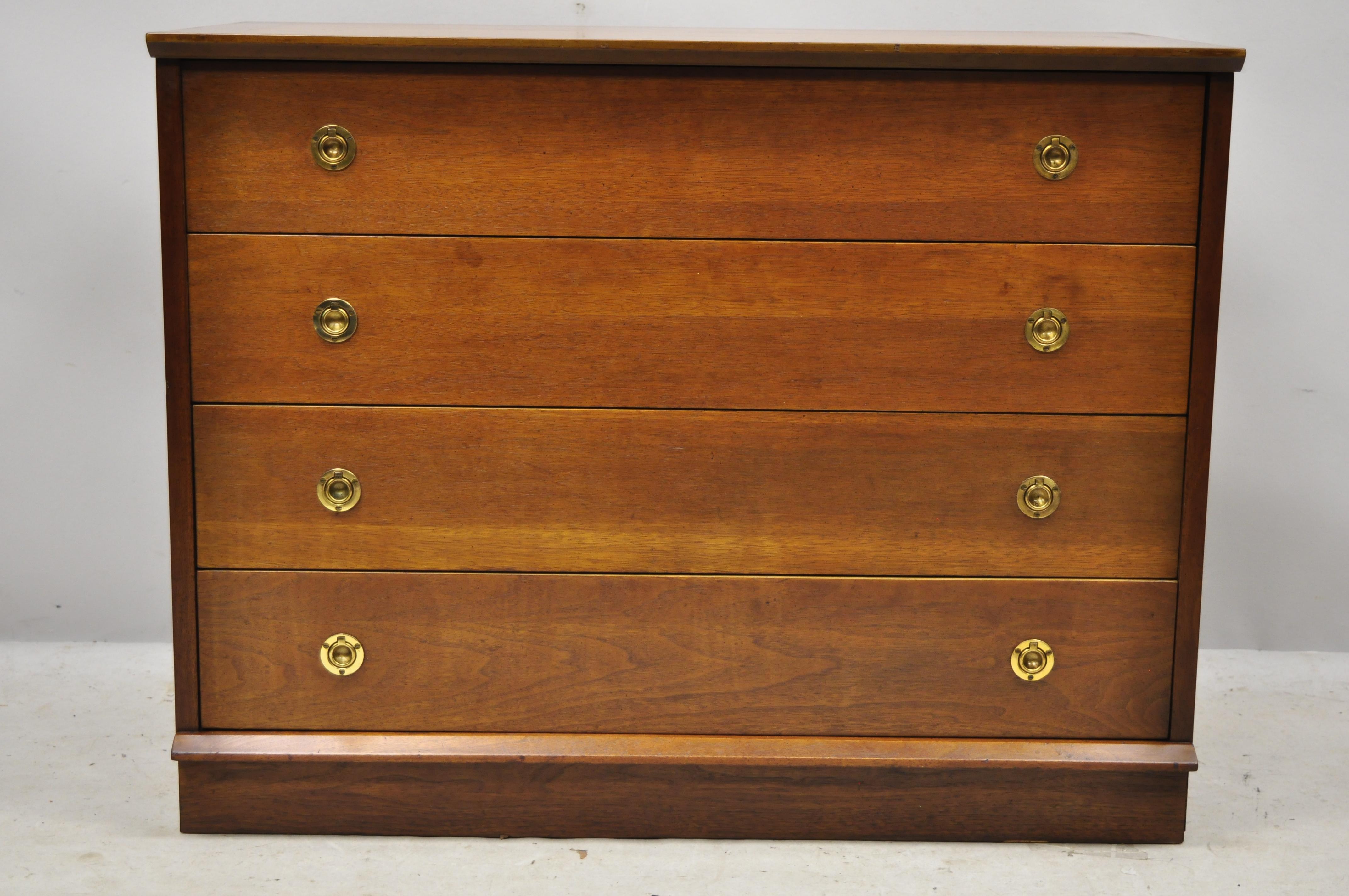 Vintage Mid-Century Modern walnut 4-drawer campaign style brass pulls bachelor chest dresser. Item features inset brass campaign style drawer pulls, angled and stapled front and rear edge, beautiful wood grain, 4 dovetailed drawers, clean modernist
