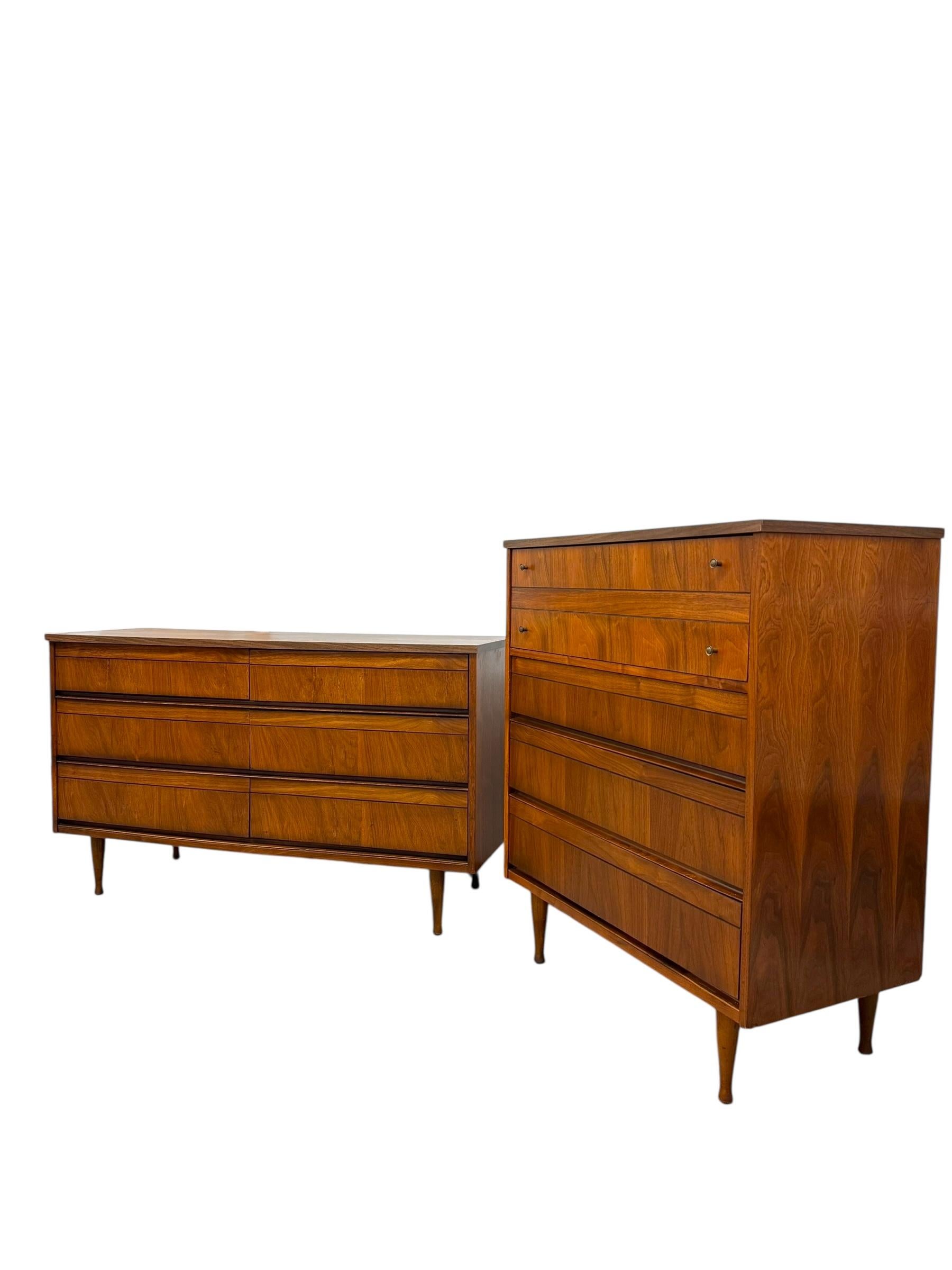 This mid-century modern dresser set, likely dating from the 1950s or 1960s, features a matching pair consisting of a low-profile triple dresser and a taller highboy chest, both crafted from walnut or similar wood veneer with a warm medium-brown