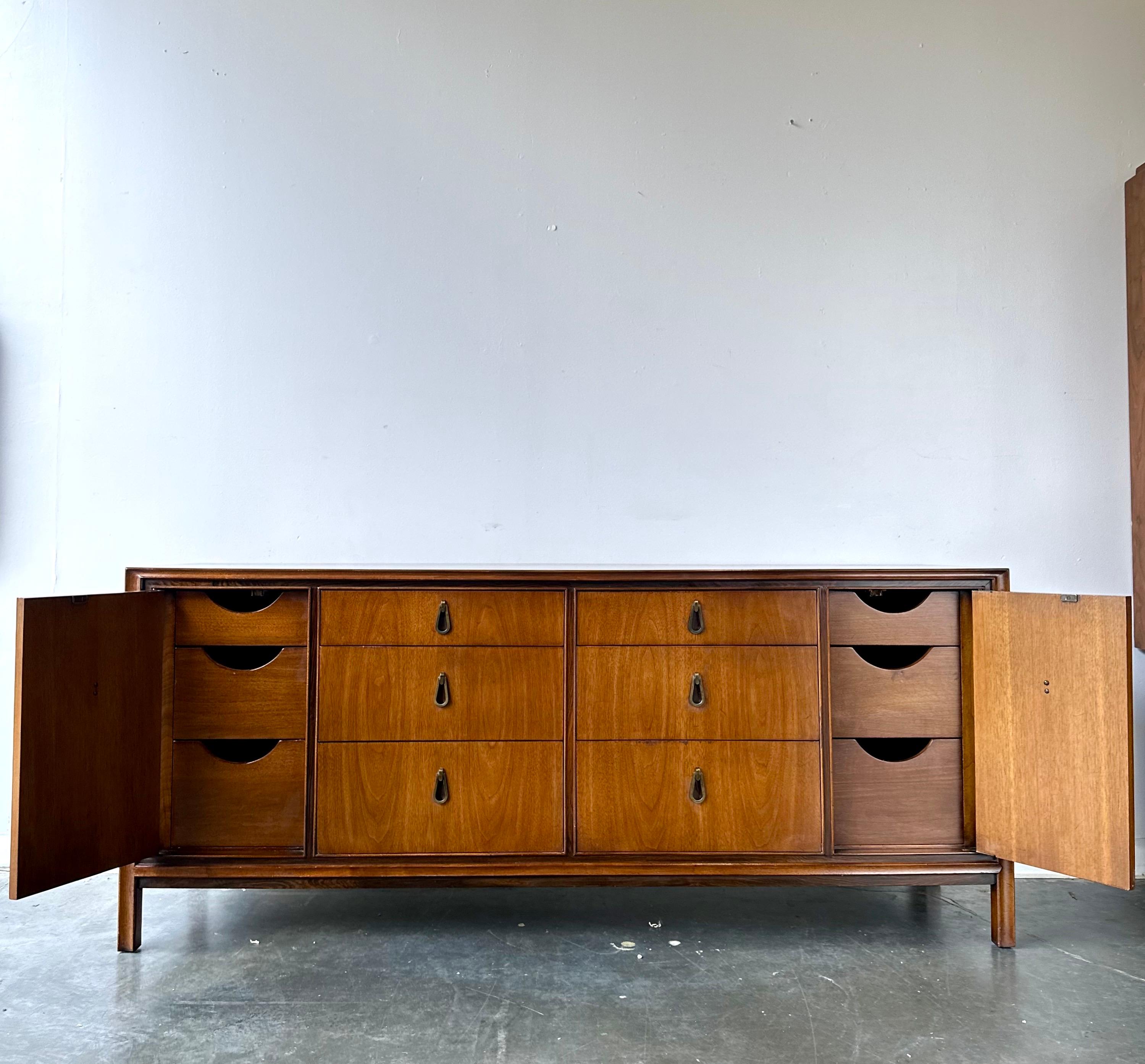 Magnifique long buffet de haute qualité conçu pour John Stuart Inc. vers 1960.

Noyer avec des accents de bois de rose et des poignées encastrées en forme de goutte d'eau.

Il est en très bon état d'origine avec des signes mineurs
