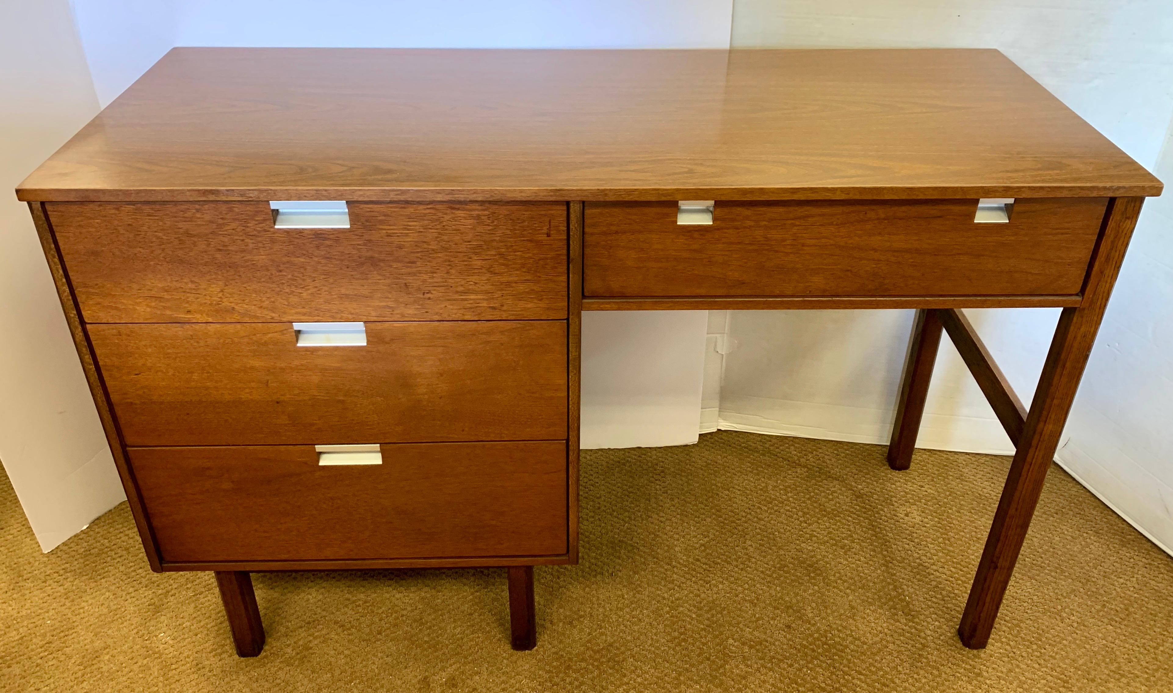 Clean lines and scale define this midcentury walnut desk with three side drawers and one smaller top drawer with original silver drawer pulls. By Basset Furniture.