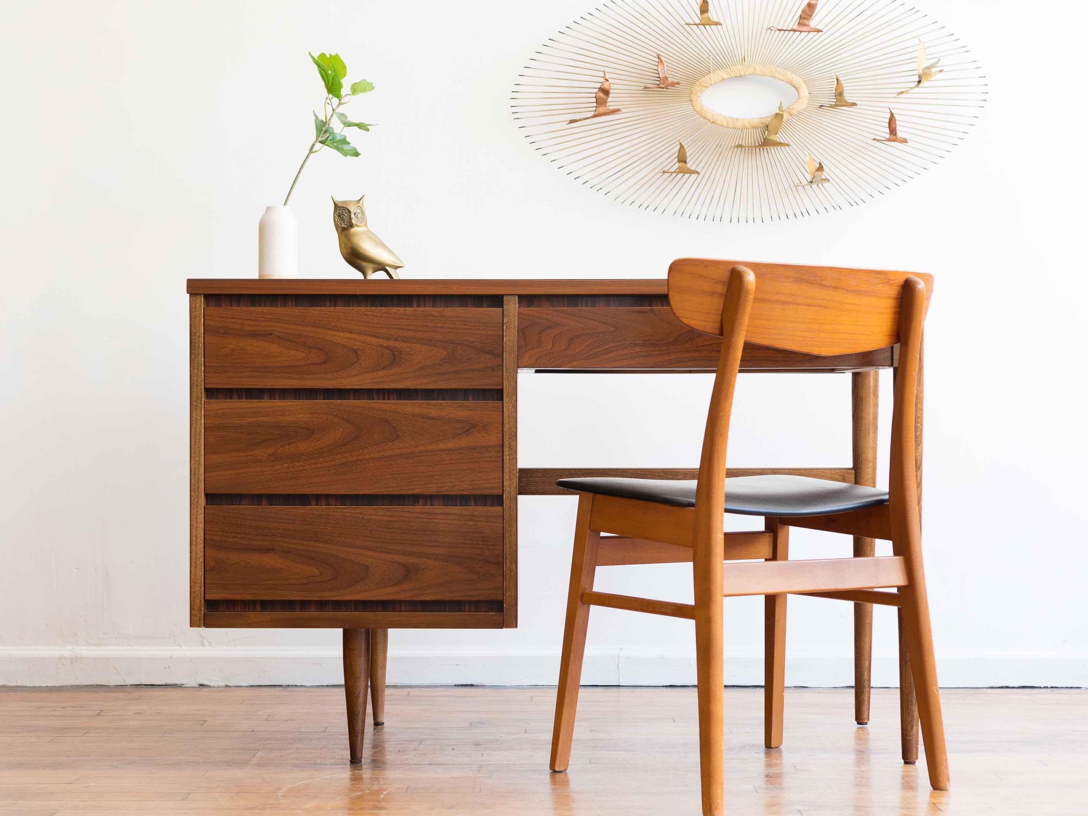 46” x 18” x 30.5”H; knee hole 23.5” x 25”H

Cute classic mid-century writing desk in walnut

•three side drawers
•smaller pencil drawer on the right
•faux rosewood trim
•tapered legs
•grain matched walnut on the drawers and top

Very good vintage