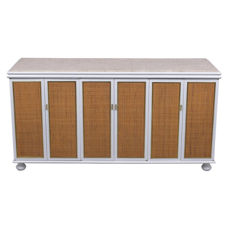 An extraordinary mid-century credenza hand-crafted out of wood in great condition has been given a new elegant white color with lacquered finish by our craftsmen team. This fabulous cabinet features a travertine marble top, six folding cane paneling