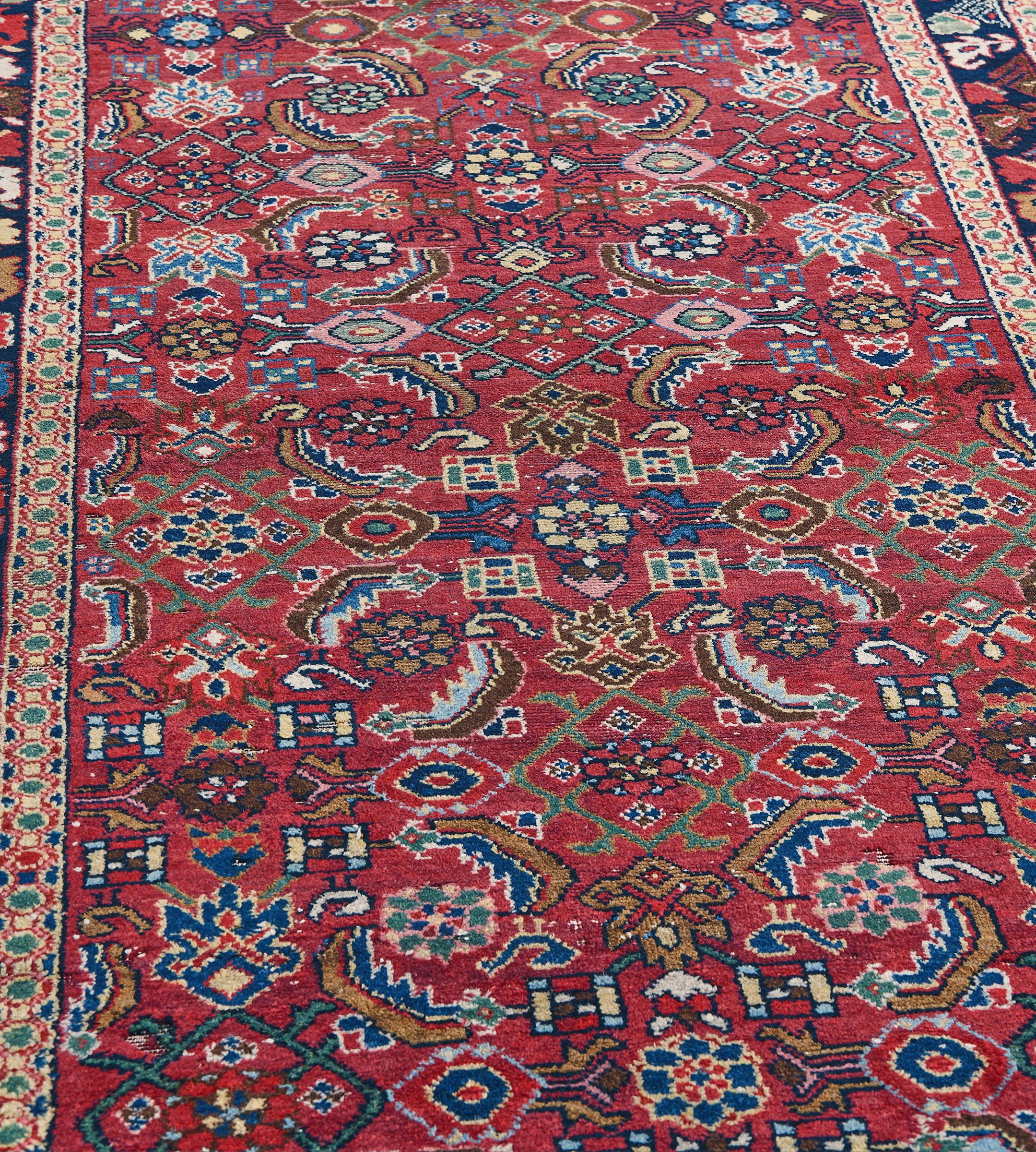 Dieser Vintage-Läufer von Malayer aus der Zeit um 1950 hat ein kirschrotes Feld mit einem polychromen Gesamtmuster aus kräftigen Herati-Mustern in einer marineblauen Bordüre mit polychromen Pflanzen zwischen sandgelben, miteinander verbundenen