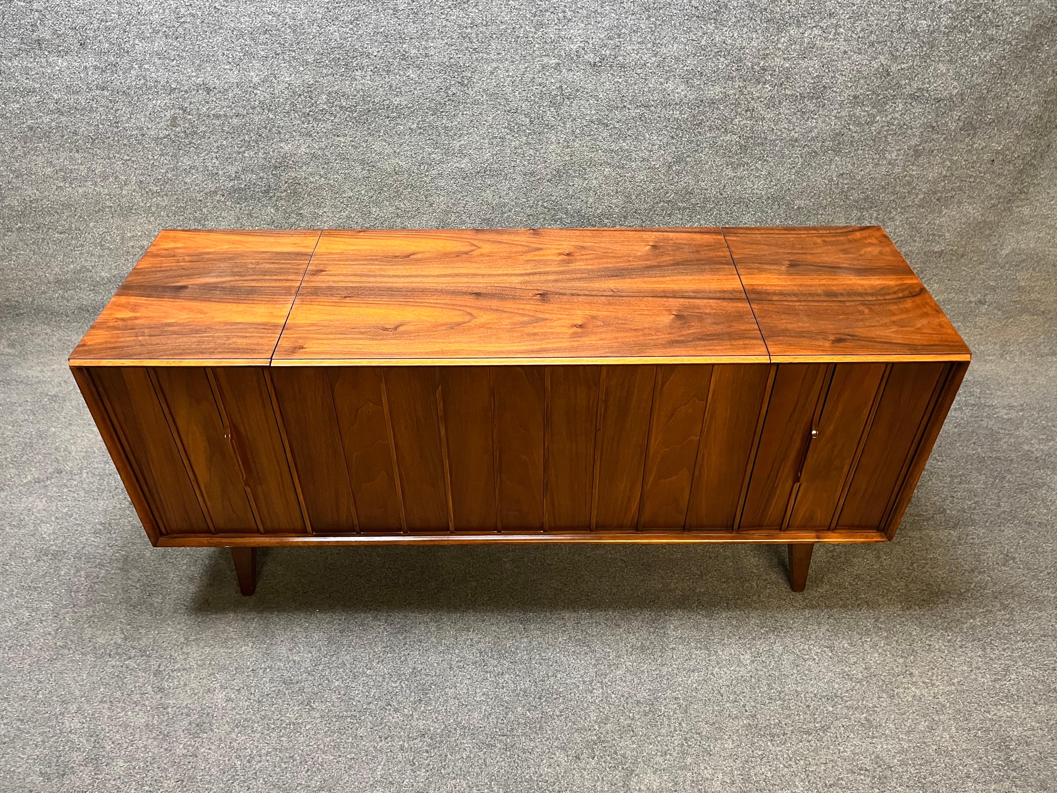 Here is a very sought after Mid century Zenith stereo console. Model X930. The top and sides have been refinished. Made of walnut with a sculptural front. Louvered doors for the speakers. No rips or tears in the speaker cloth. The radio works and
