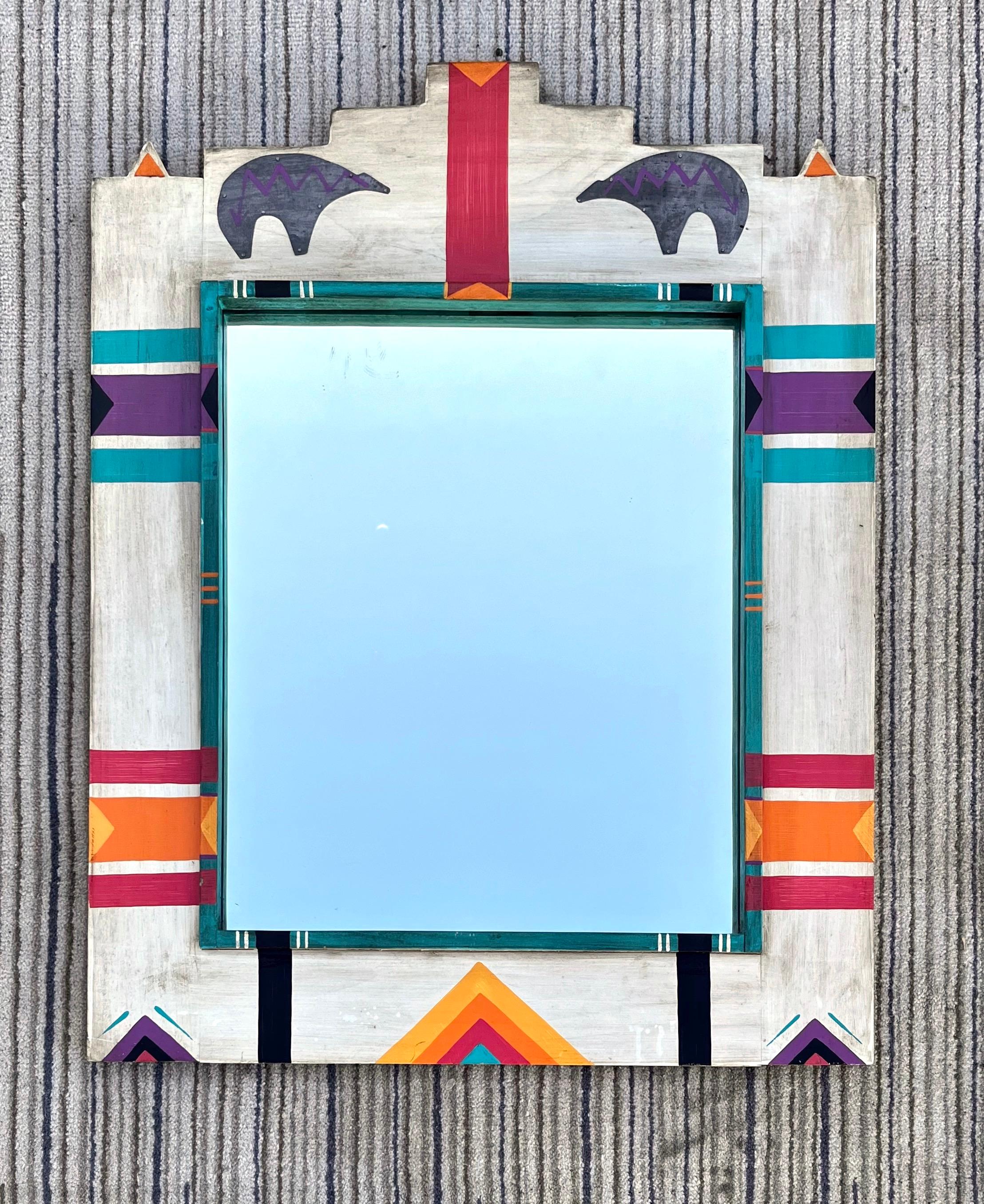 Specchio da parete vintage di medie dimensioni ispirato all'arte dei nativi americani. circa anni '80
Presenta una cornice in legno massiccio dipinta a mano in bianco sporco con due orsetti in lamiera zincata applicati. 
In eccellenti condizioni