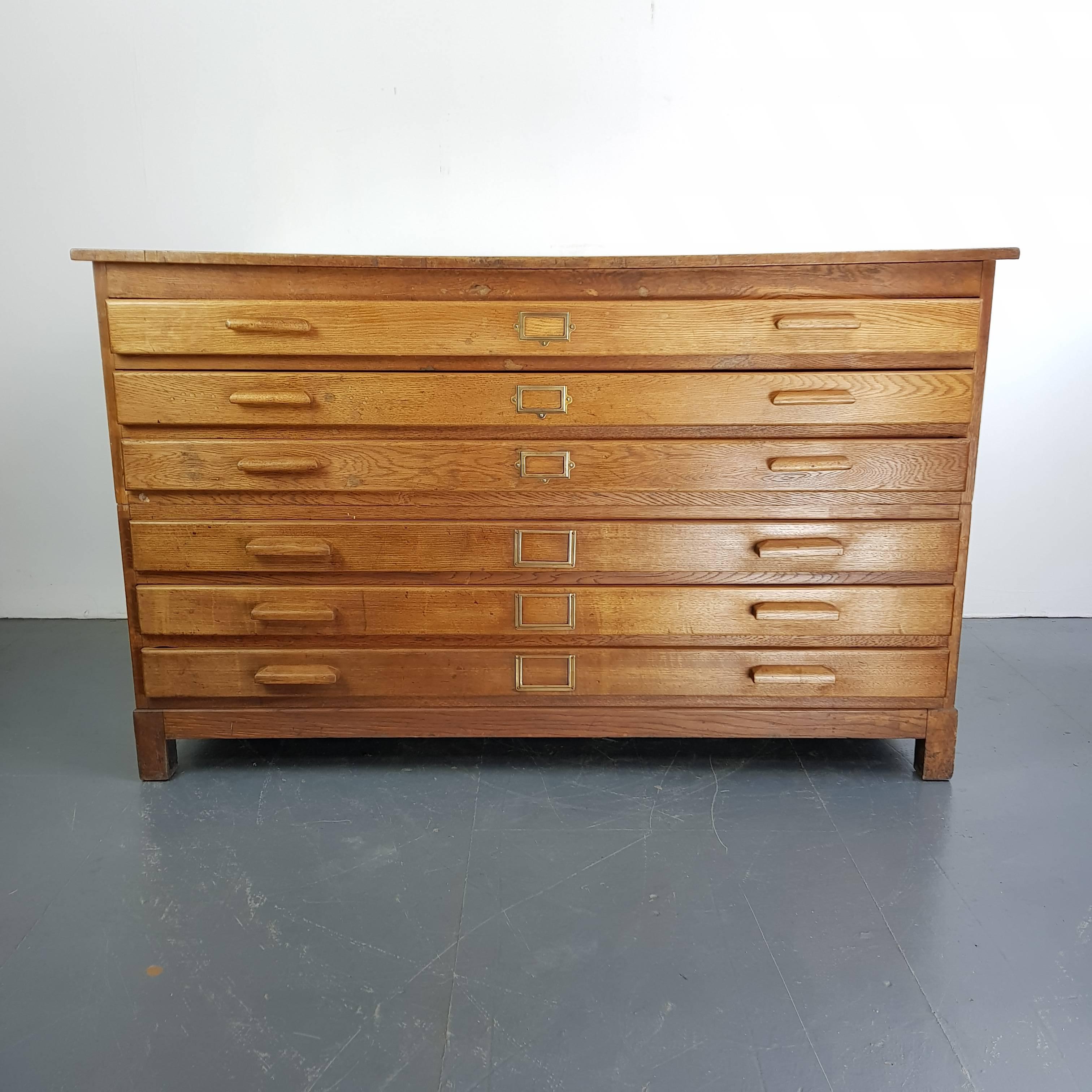 Lovely oak six drawer midcentury plan chest with wooden handles and brass label inserts and panelled sides.

The plan chest has six solid wooden drawers and panelled sides.

Approximate dimensions: 

Height 93 cm

Width 151 cm

Depth 102