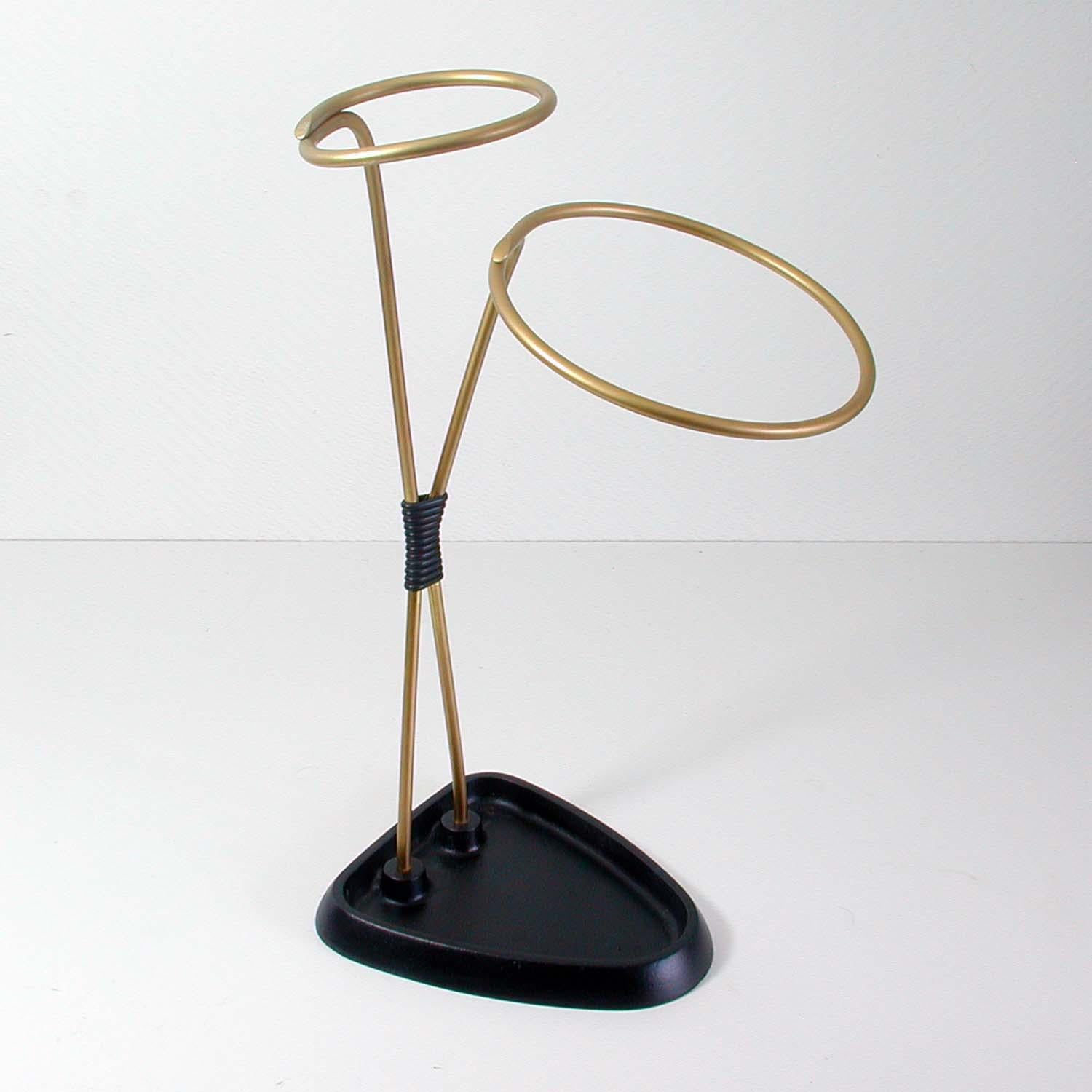 This midcentury vintage umbrella stand was made in Austria in the 1950s.
It is made of gold anodized metal and has got a black lacquered cast iron base.