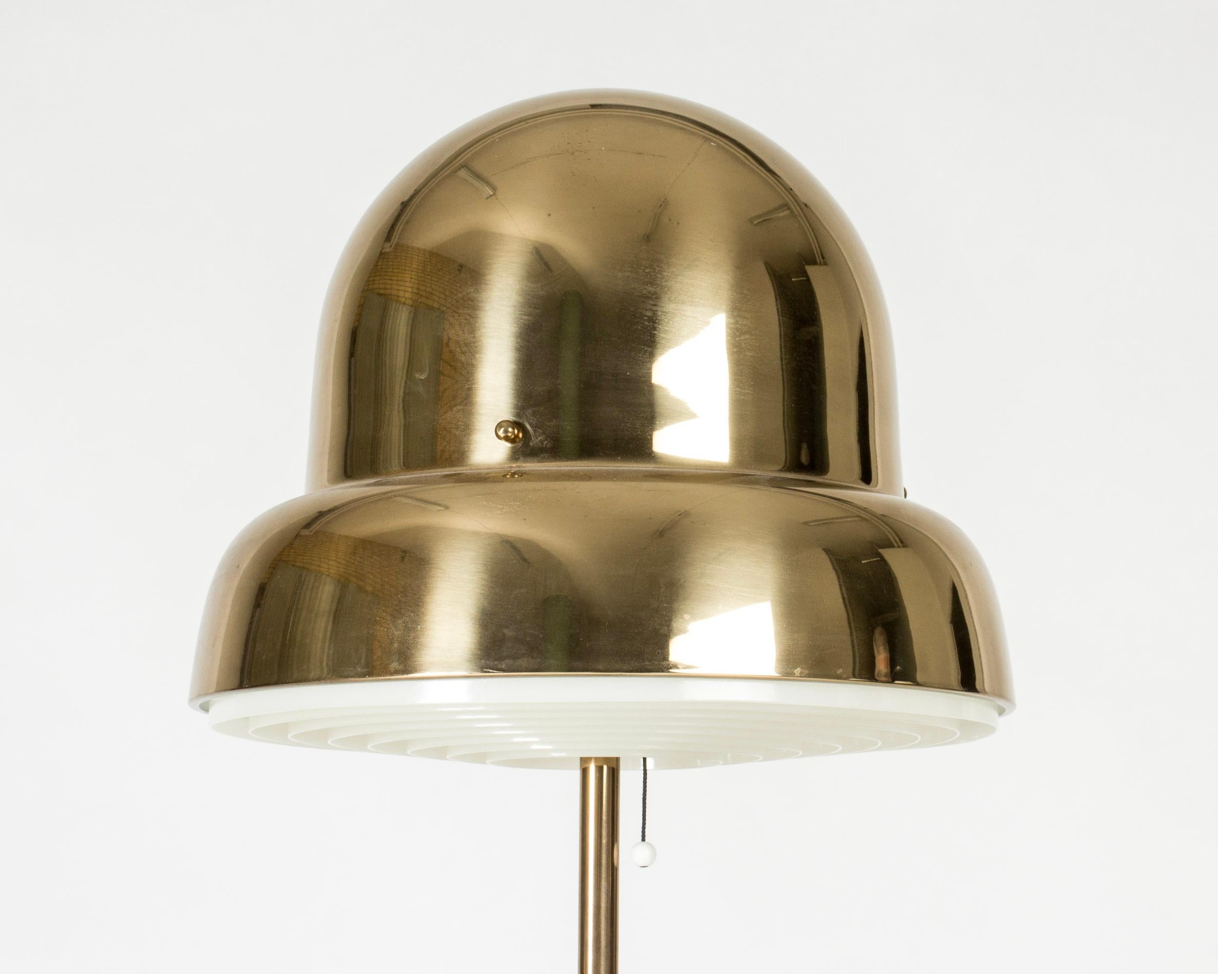 Cool brass floor lamp from Bergboms, with an oversized lampshade in a rounded, organic form. Lamellas shield the light on the underside.