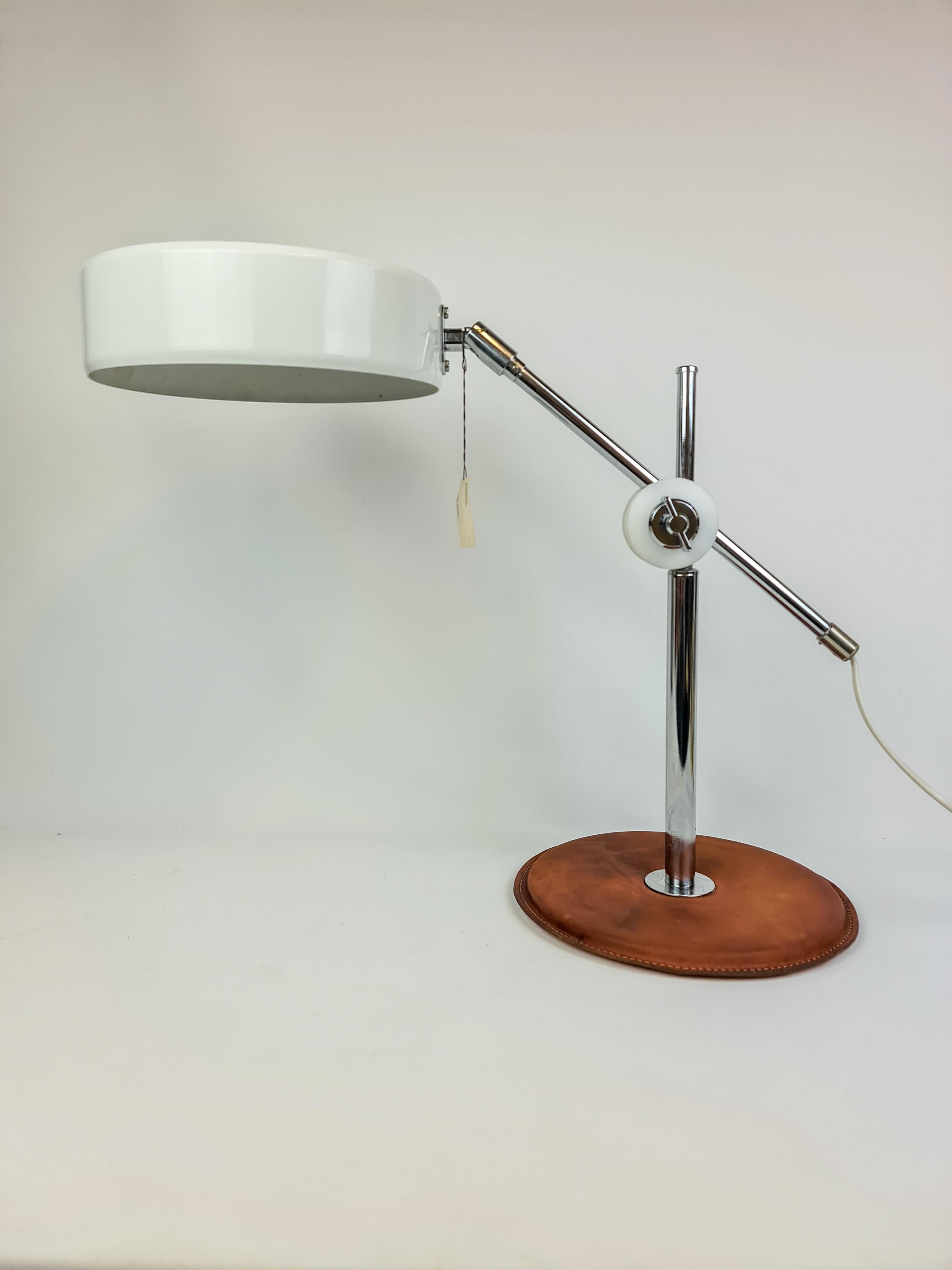This Simris table lamp was designed by Anders Pehrson for Atelje Lyjktan Sweden in the early 1970s. It has a nice patinated brown leather base and chrome details to the lamp and white shade in metallic. 

Fully functional, complete. Original label