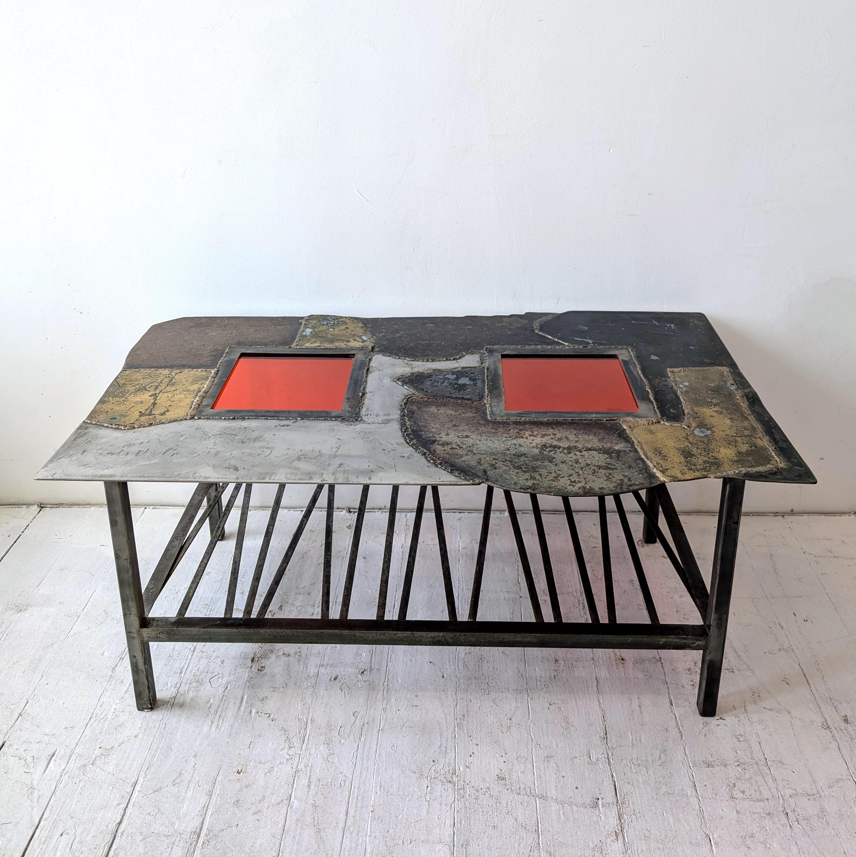 Unusual Brutalist steel & brass coffee table with tomato red glass panels, USA 1970s.

Good condition: some slight wear to metal, commensurate with the age of the piece.

Dimensions: length 106cm, width 63cm, height 43cm
