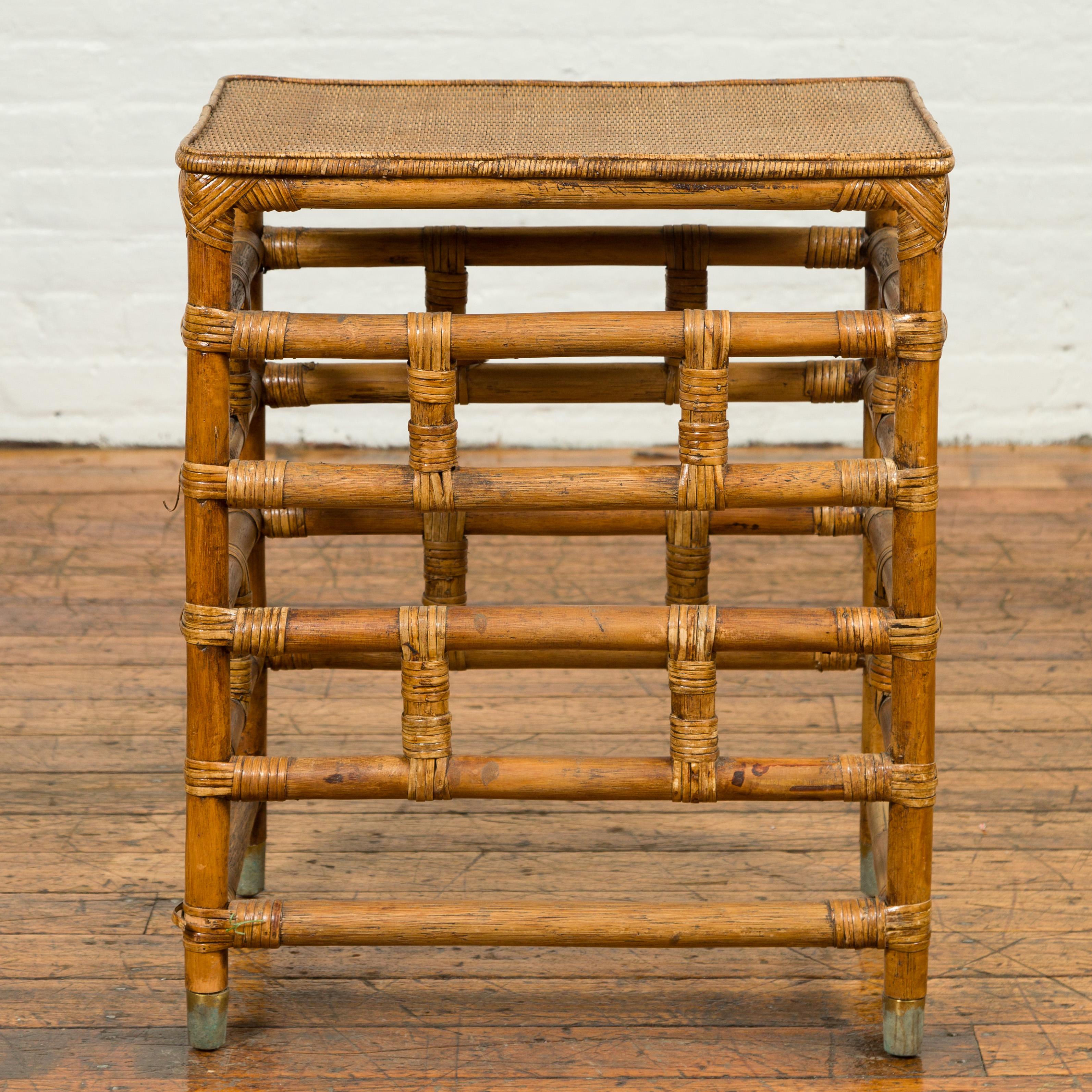 A vintage Burmese bamboo side table from the mid-20th century, with rattan top. Born in Myanmar during the midcentury period, this stylish side table features a linear silhouette made of a geometrically organized bamboo base. Presenting a rattan
