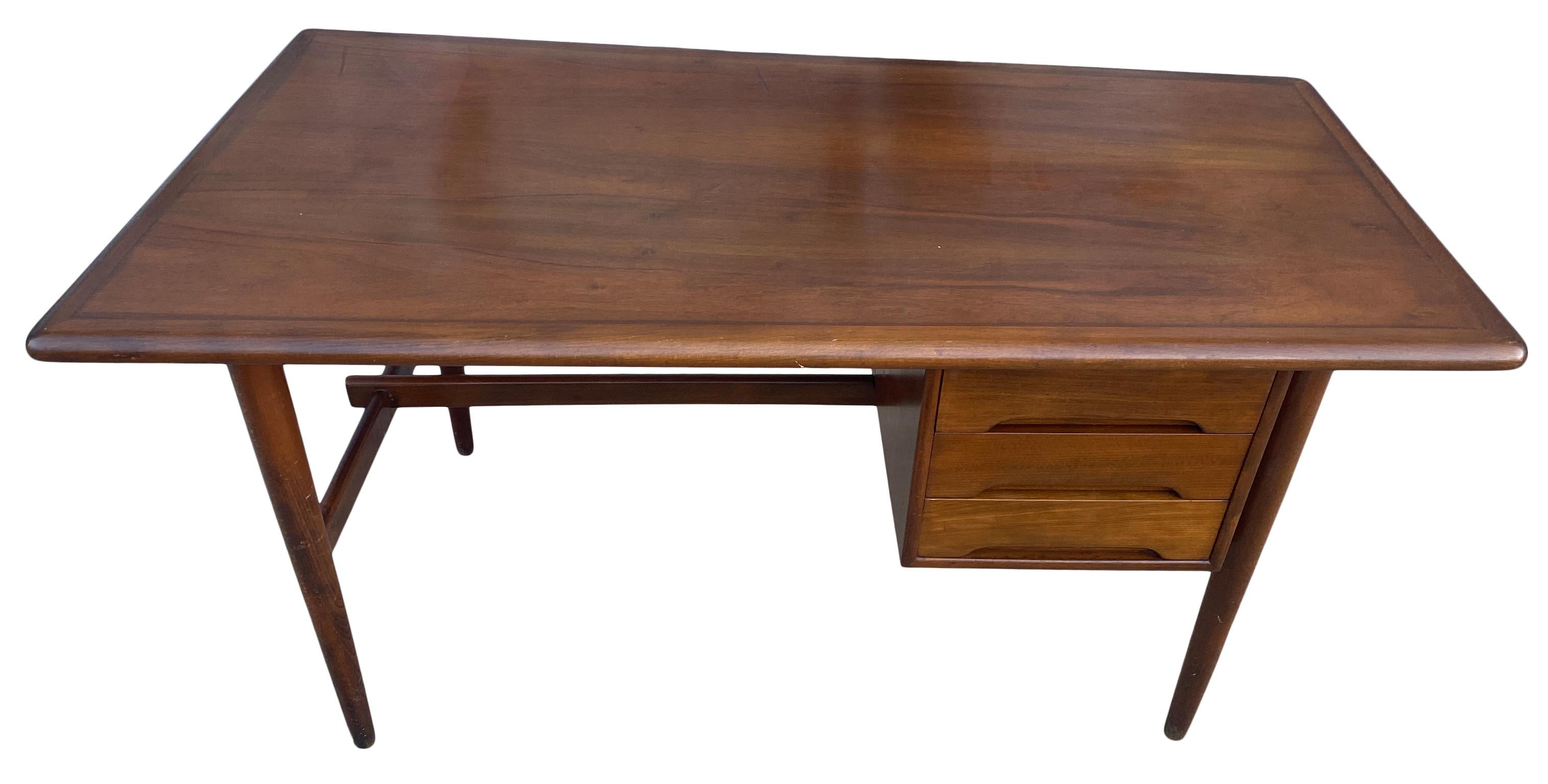 Great vintage midcentury Danish modern writing desk 3 drawer Denmark asymmetrical top. Stunning Danish design with round tapered legs and a lower crossbar. Labeled, made in Denmark. Solid wood desk. Beautiful design. Shows some wear on top surface.