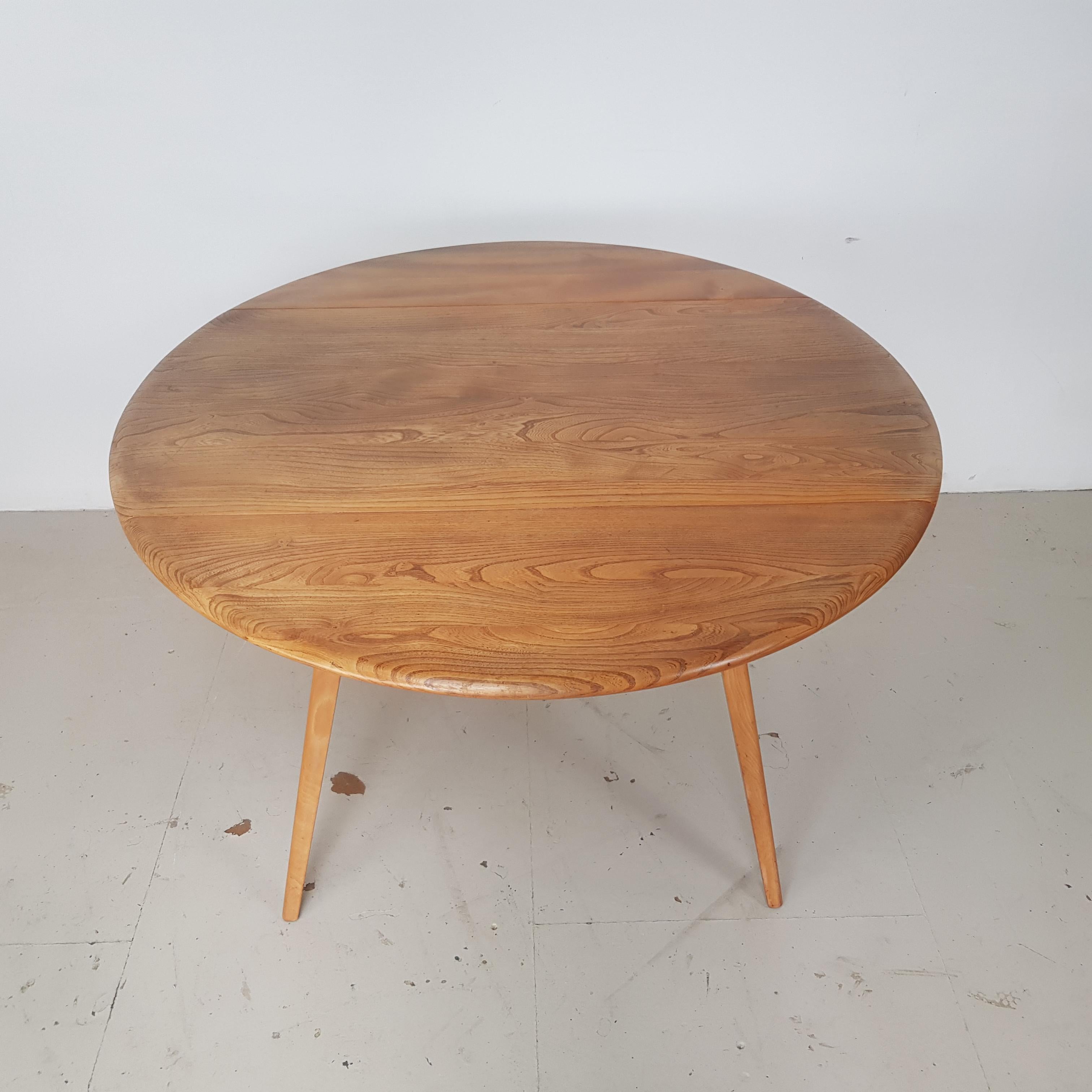 Lovely vintage (mid-1960s) Ercol round drop leaf dining table. Lovely elm top on beech legs. 

In very good vintage condition. It's a vintage item, so has some general age-related wear, but nothing specific to mention.

Approximate