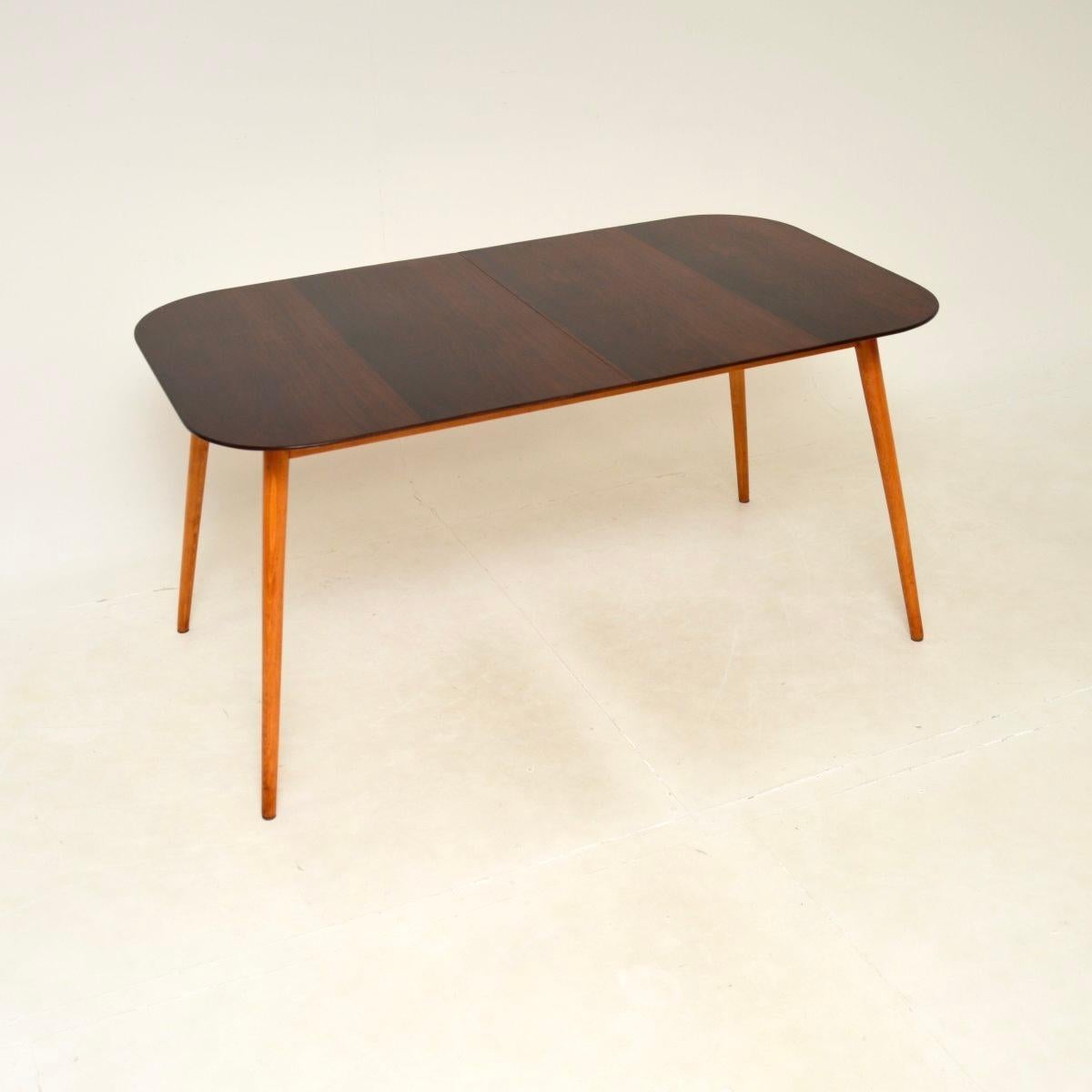 Une table à manger extensible vintage extrêmement élégante et bien faite, fabriquée en Angleterre et datant du début des années 1950.

Ce meuble est d'une conception étonnante, avec un magnifique bord chanfreiné fin, et repose sur de magnifiques