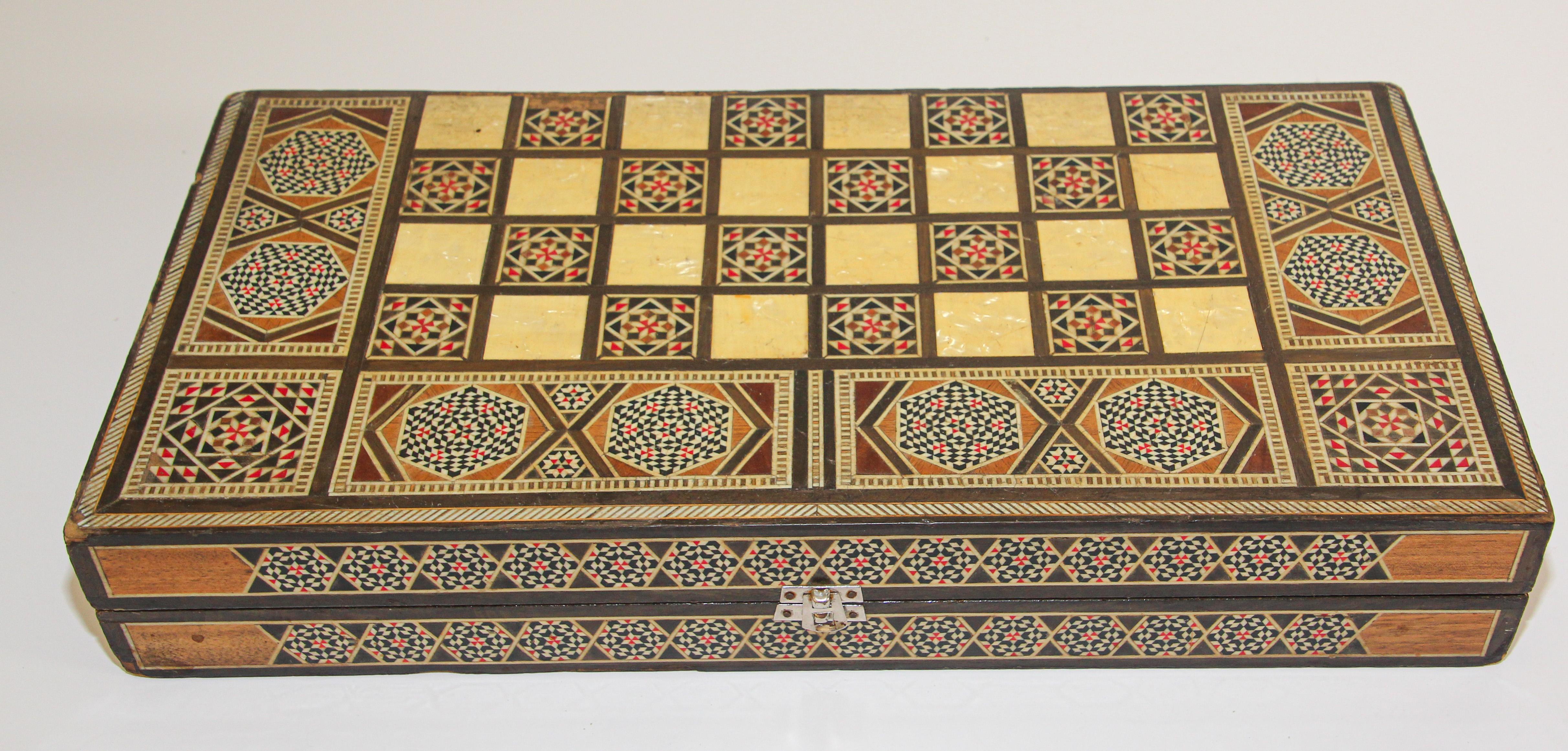 Large vintage midcentury folding box inlaid with mother of pearl mosaic backgammon game.
Middle Eastern folding game box inlaid with micro mosaic marquetry features a chess and checker board on the exterior and backgammon board on the interior with