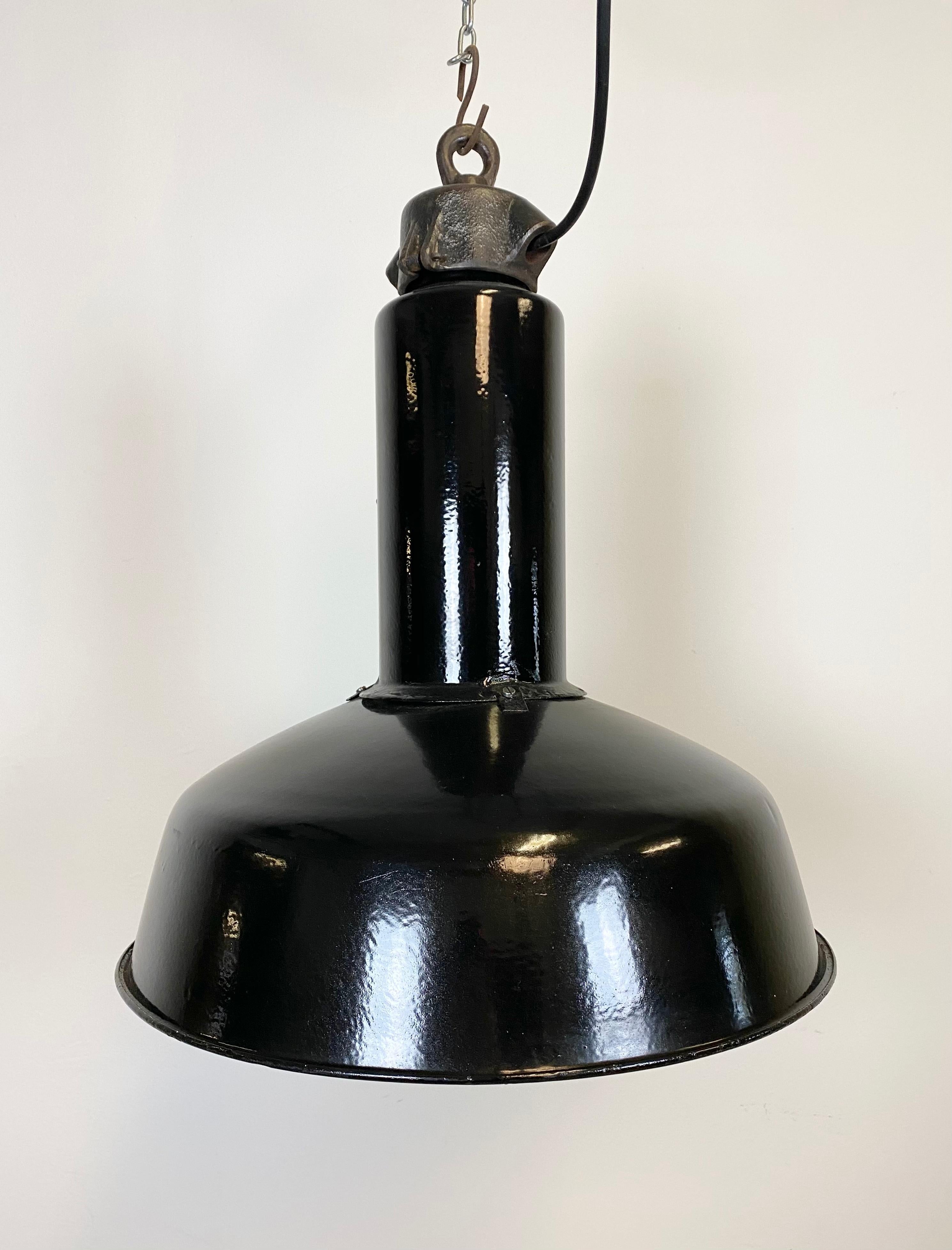 This industrial lamp was made in former Czechoslovakia during the 1950s. It features black enamel exterior , white interior. Cast iron top. New porcelain socket for E 27 lightbulbs and wire. The weight of the lamp is 3 kg.