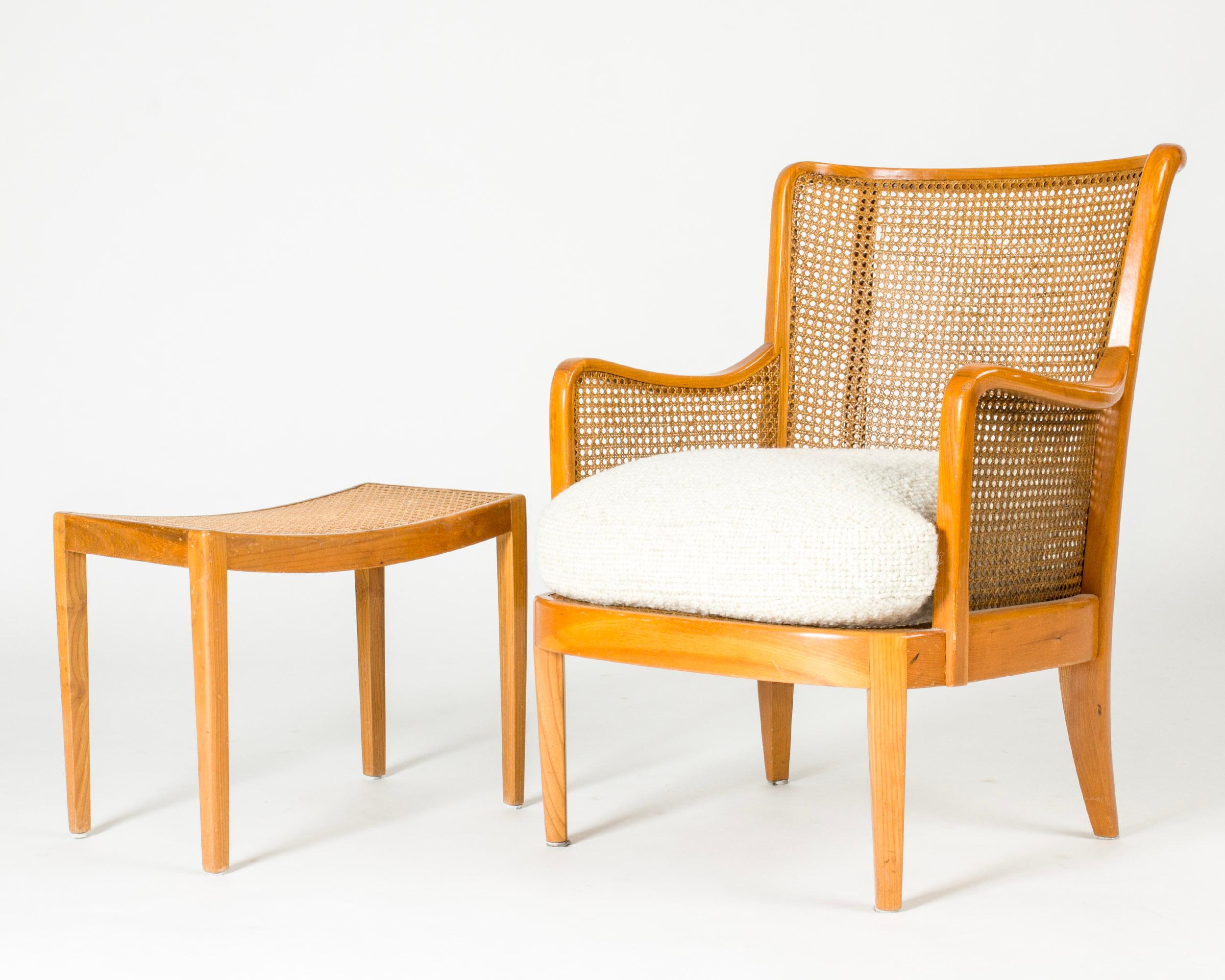 Beautiful lounge chair by Margareta Köhler, made from mahogany with a very decorative rattan back and sides. Voluminous bouclé seat.

Footstool also made from mahogany with a rattan seat.
