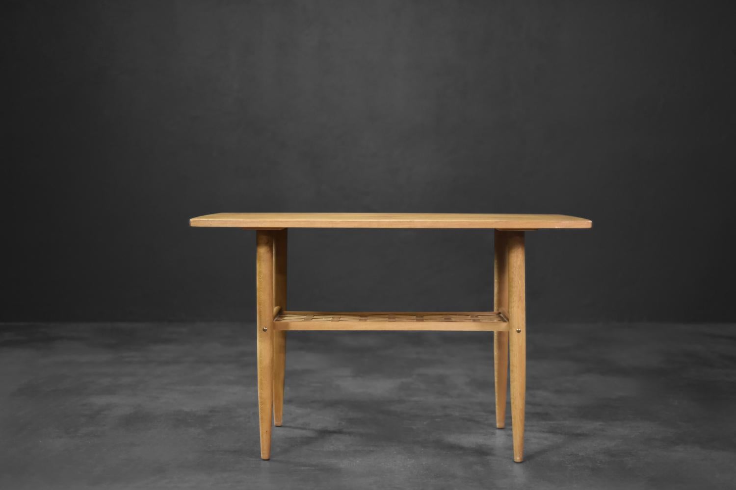 Cette petite table basse a été produite en Scandinavie dans les années 1960. Il était en bois de cerisier. Il est très attrayant, dur et en même temps flexible et résistant aux charges mécaniques. La table est dotée d'une étagère tressée très