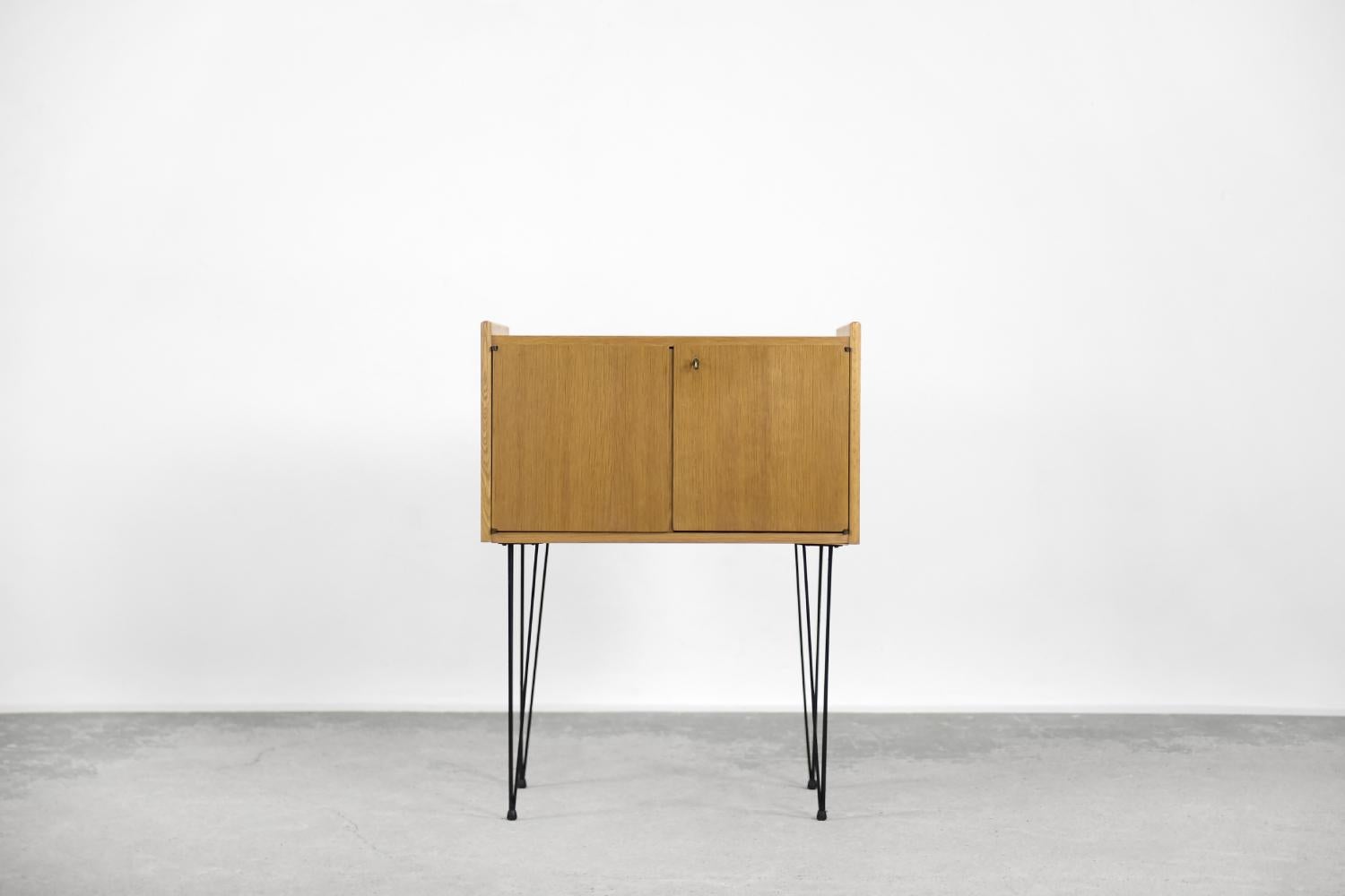 This modernist cabinet was made in Sweden during the 1960s. It is finished with teak wood in a cool shade of brown. The cabinet is locked with a key and there is a spacious space inside. Cabinet is mounted on metal, black hairpin legs. The cabinet