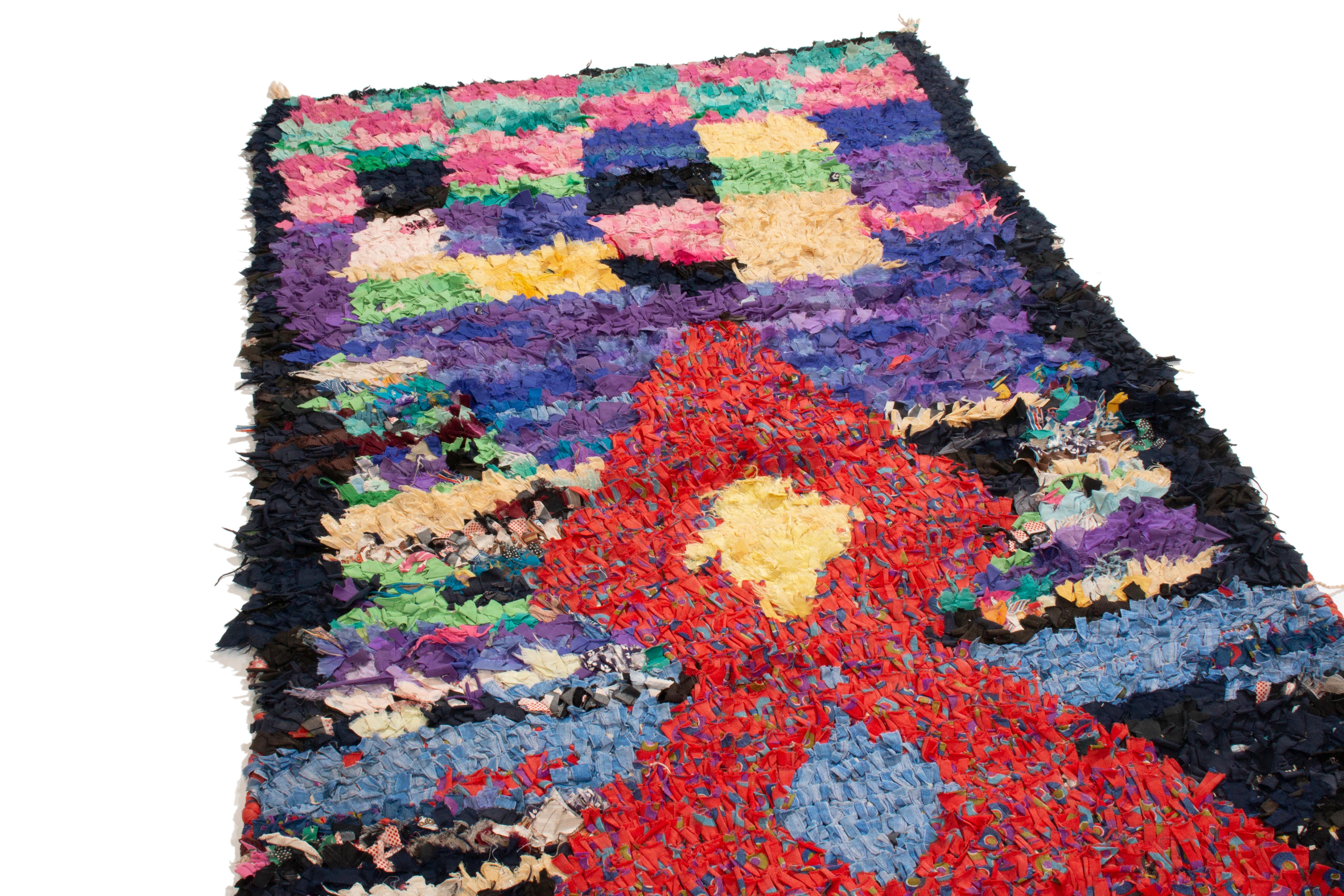 Originating from Morocco in the 1950s, this vintage midcentury Moroccan fabric rug depicts a culturally vital symbol in transitional style. The prominent red geometric emblem with sparks of blue, purple, and green is reminiscent of the Moroccan