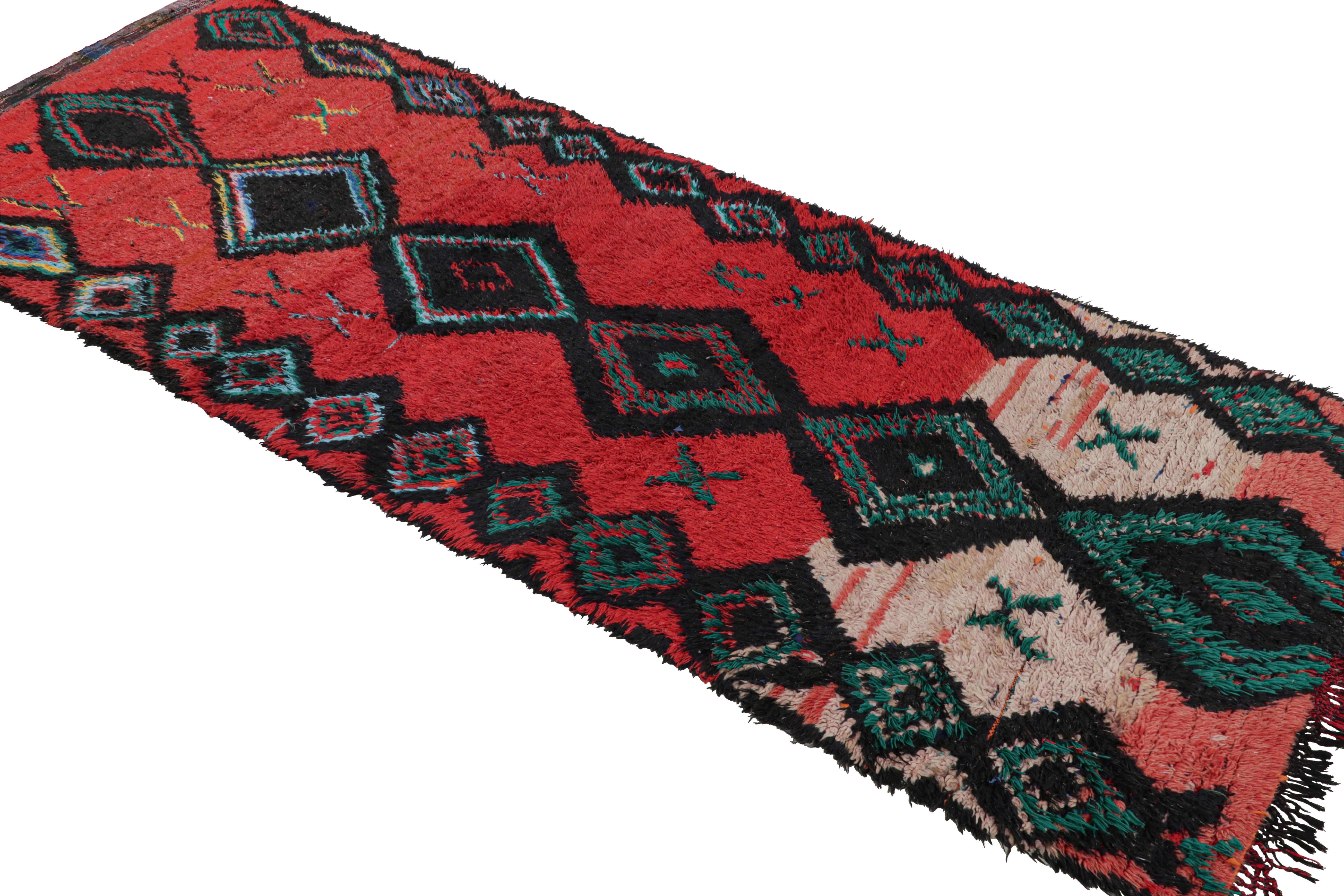 Originario del Marocco degli anni '50, questo tappeto vintage in lana marocchina della metà del secolo scorso simboleggia forza, protezione e femminilità grazie alla combinazione di audaci colori rossi e losanghe a forma di diamante. Annodate a mano