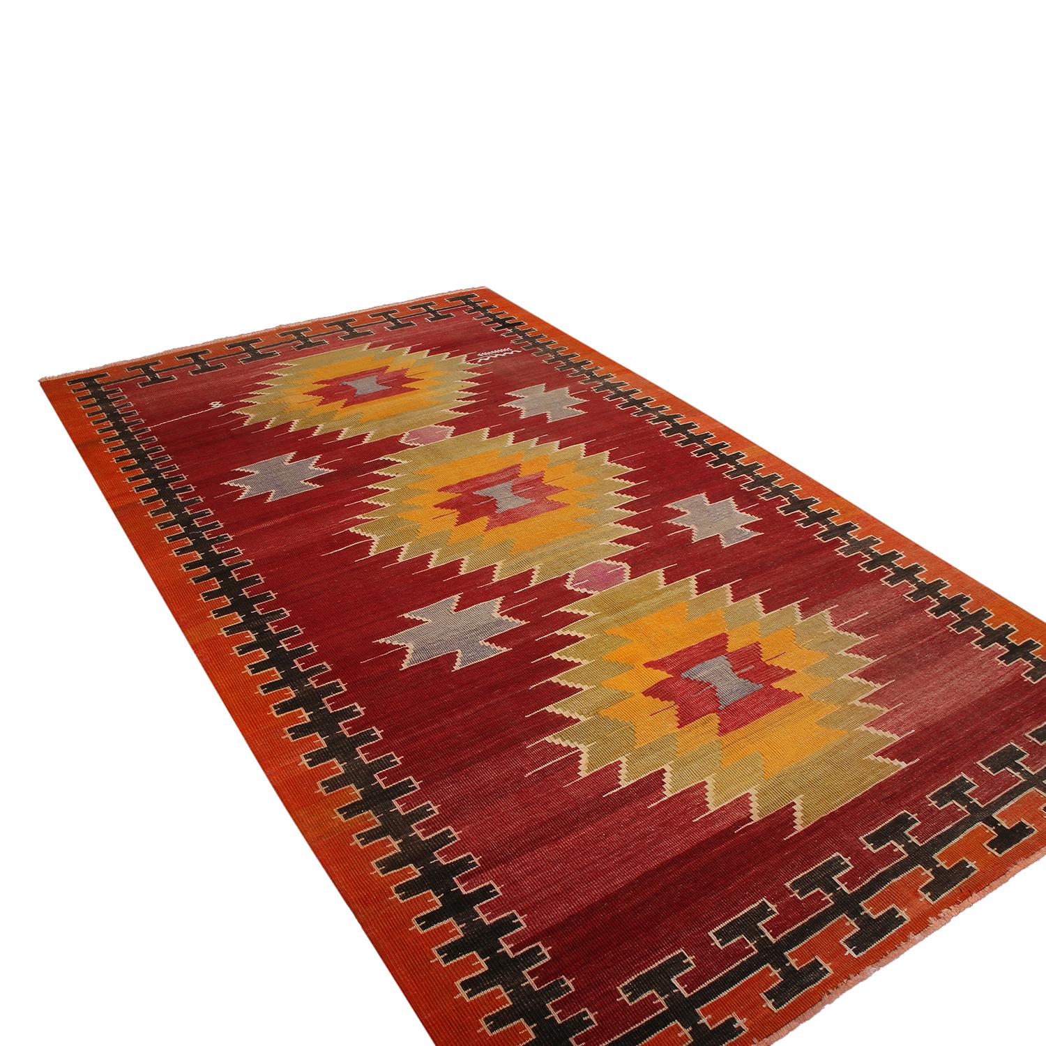flat-woven in Turkey originating between 1950-1960, this vintage midcentury Mut Kilim rug presents a lively tribal array of red, orange, green, yellow and blue hues in the colorway highlighting the tastefully abrashed background with a crisp