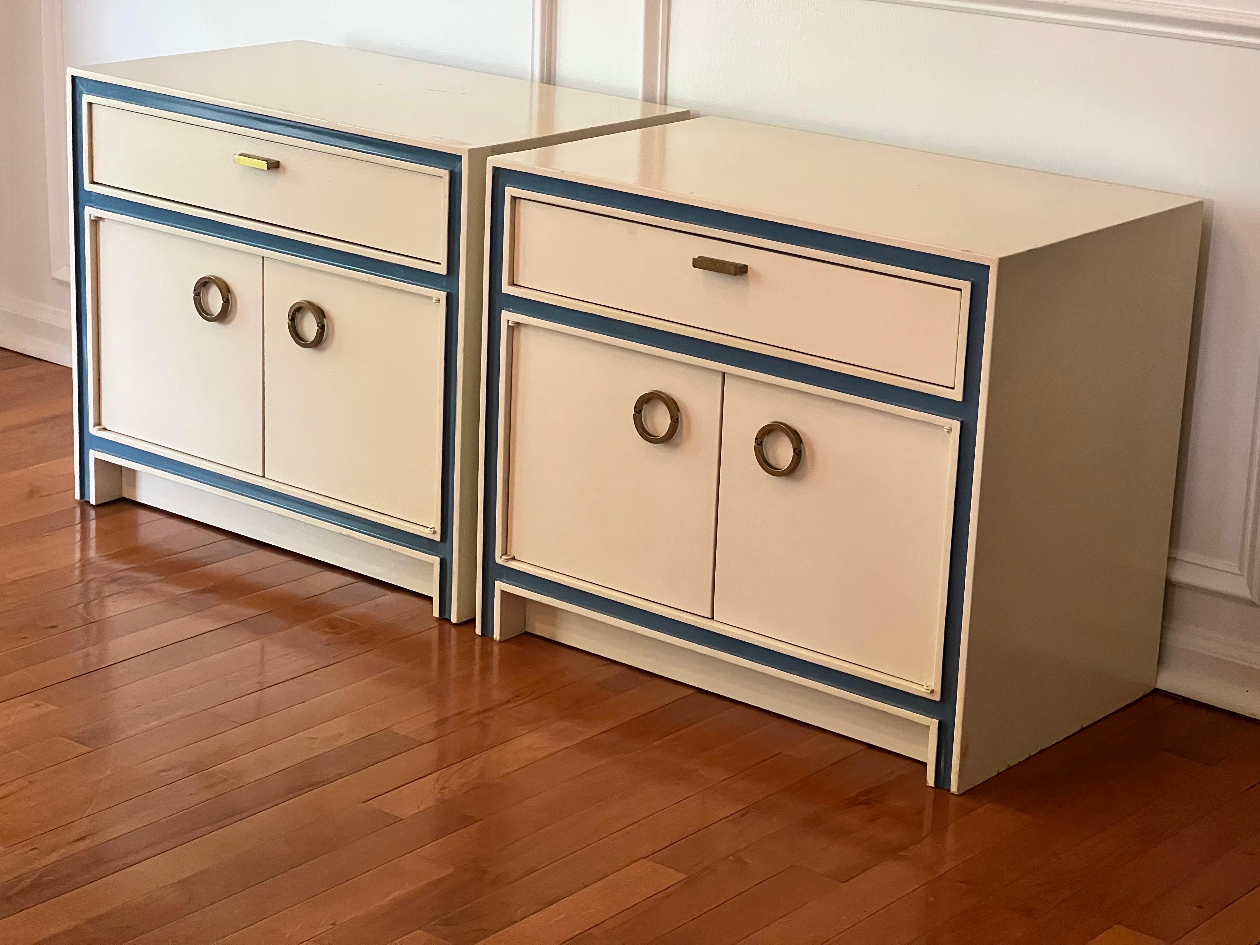 Vintage mid-century nightstands by Hickory Manufacturing Company. The pair is painted in a soothing cream color with French blue accent border highlighting the geometrical design. They each feature a single dovetail drawer and two-door cabinet with