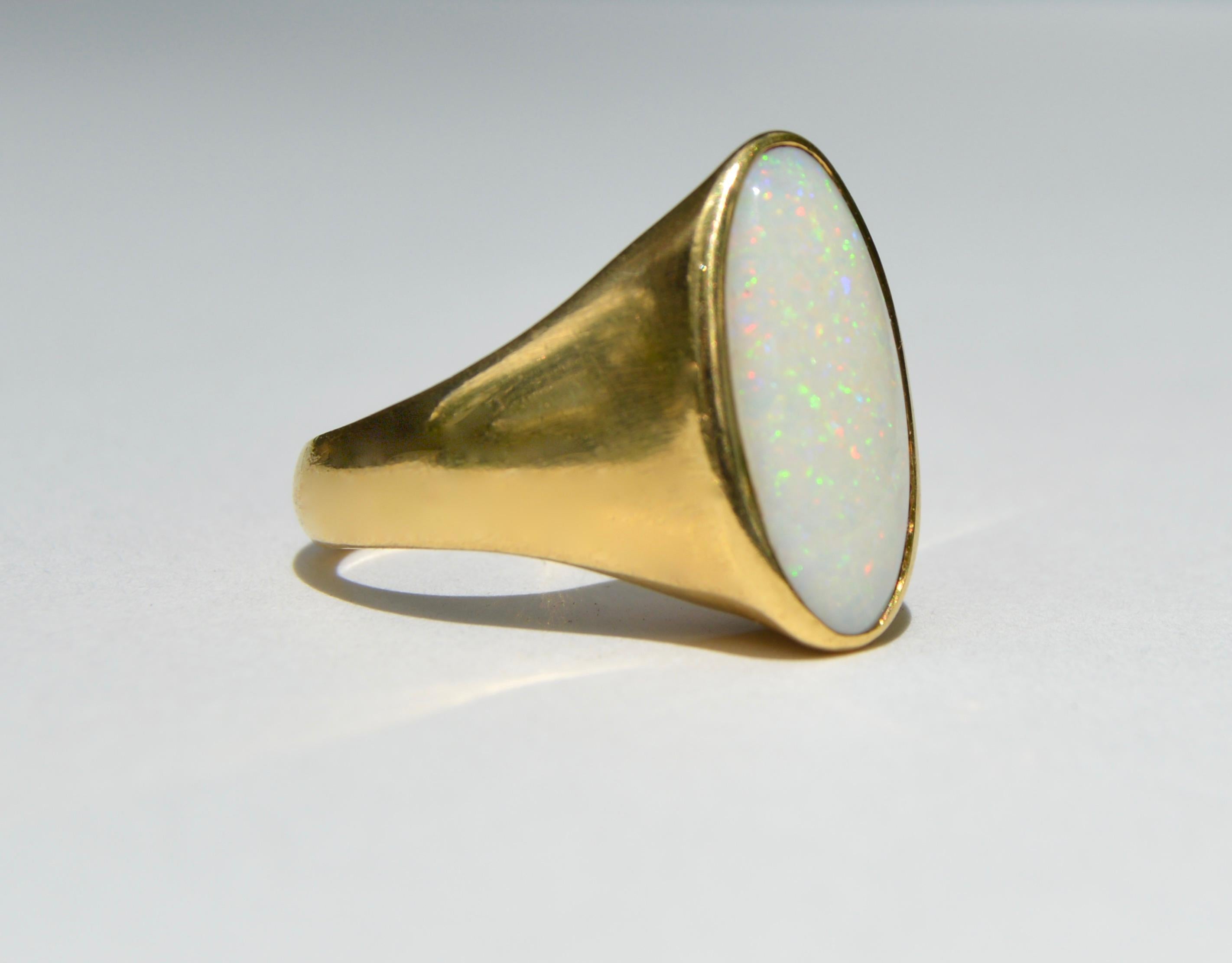Beautiful Midcentury era circa 1960s 14K yellow gold natural opal oval cabochon signet ring. Size 7, can be resized by a jeweler. Ring is unmarked but tested as solid 14K gold. The rainbow flecked fiery opal measures 17x8mm. In very good condition.
