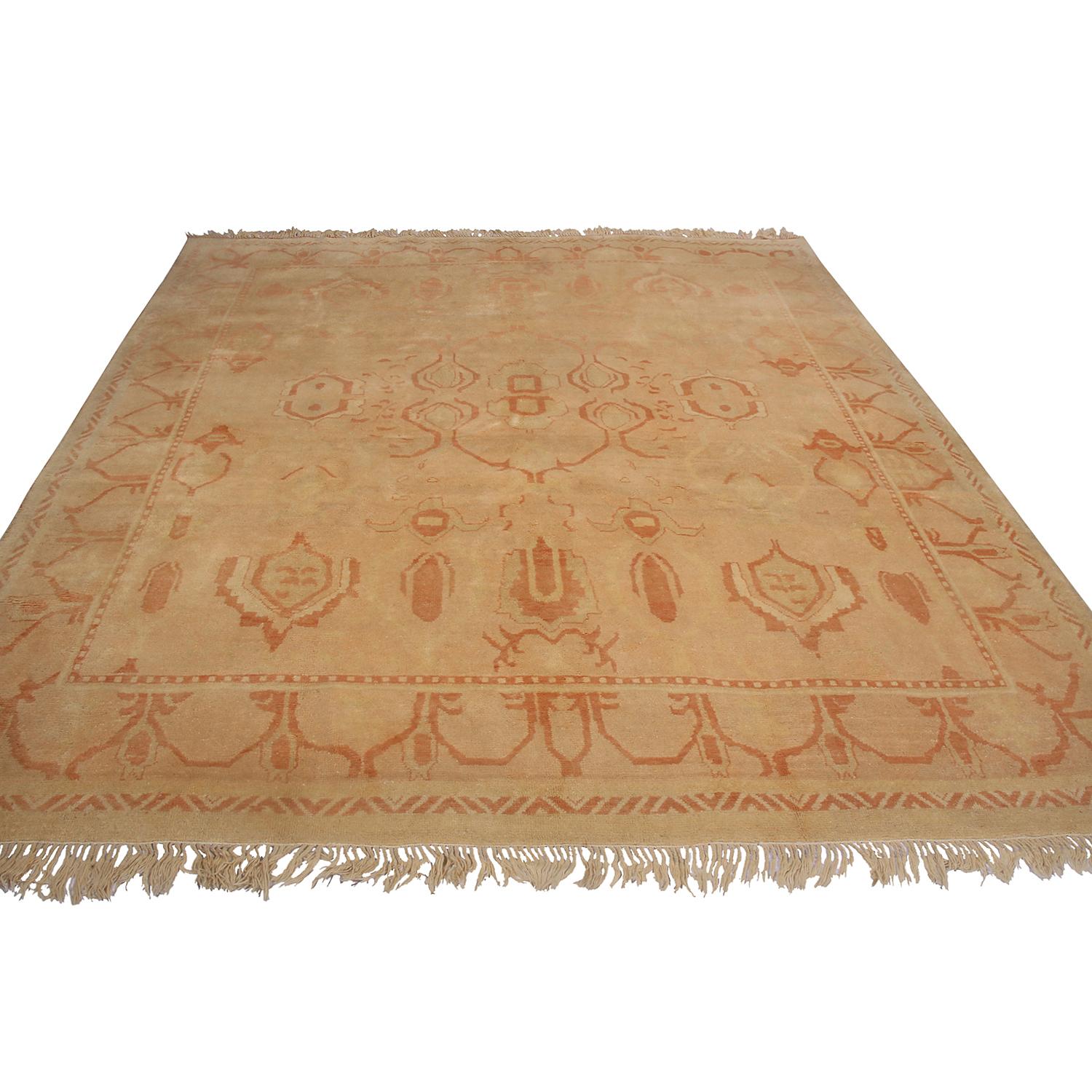Hand knotted in Turkey originating between 1950-1960, this vintage midcentury Oushak rug enjoys a warm, inviting colorway complementing a very mild, natural wear in the field. The radiant beige and peach-orange tones play beautifully off the subtly