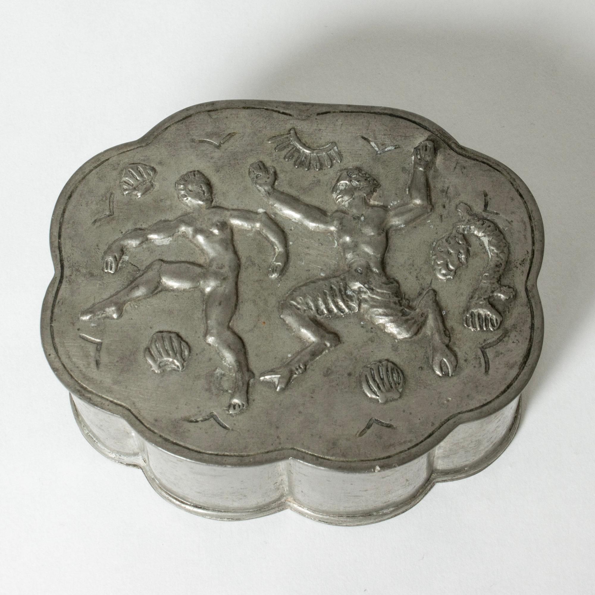 Lovely pewter box from Herman Bergman, in oval shape with a scalloped silhouette. Decor of a lively woman and a faun among shells and coral. Pretty etched pattern on the lid and around the base.