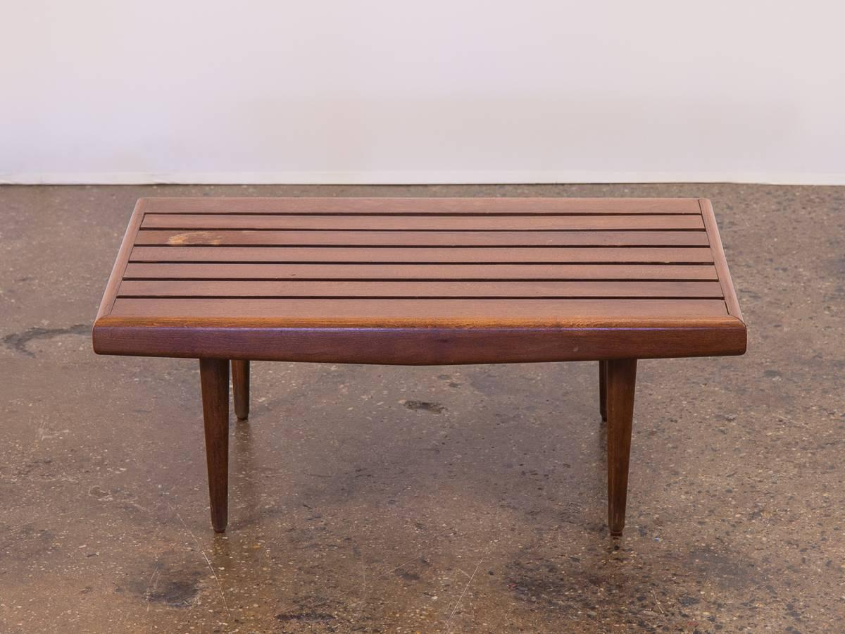 Short, midcentury slat bench or side table. A timeless modern design that adds architectural warmth to the home whether as seating or side table. Our example is from the 1960s, and is in very good vintage condition. The hardwood bench’s surface and